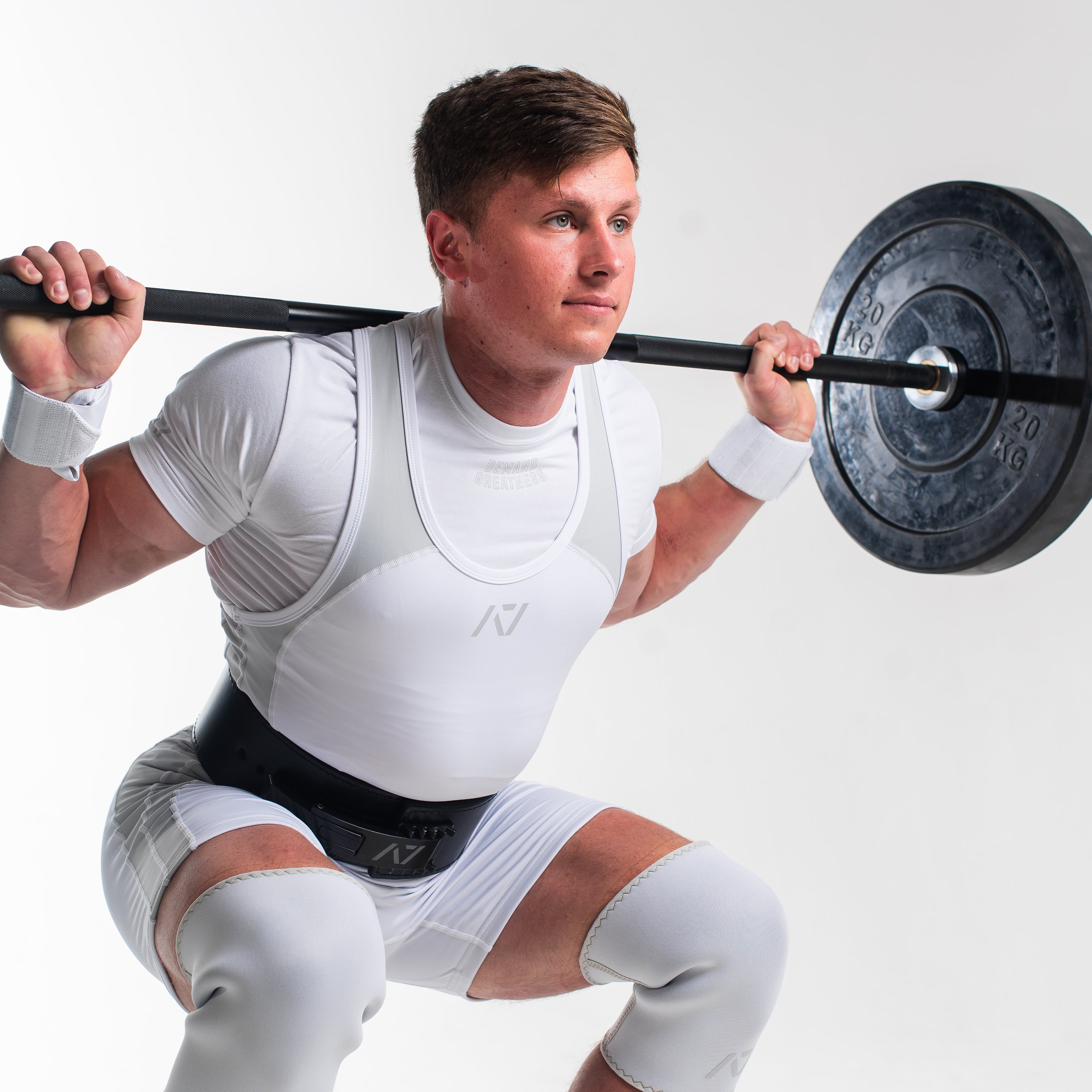 Man lifting in polar meet kit with a barbell with weights on a white background