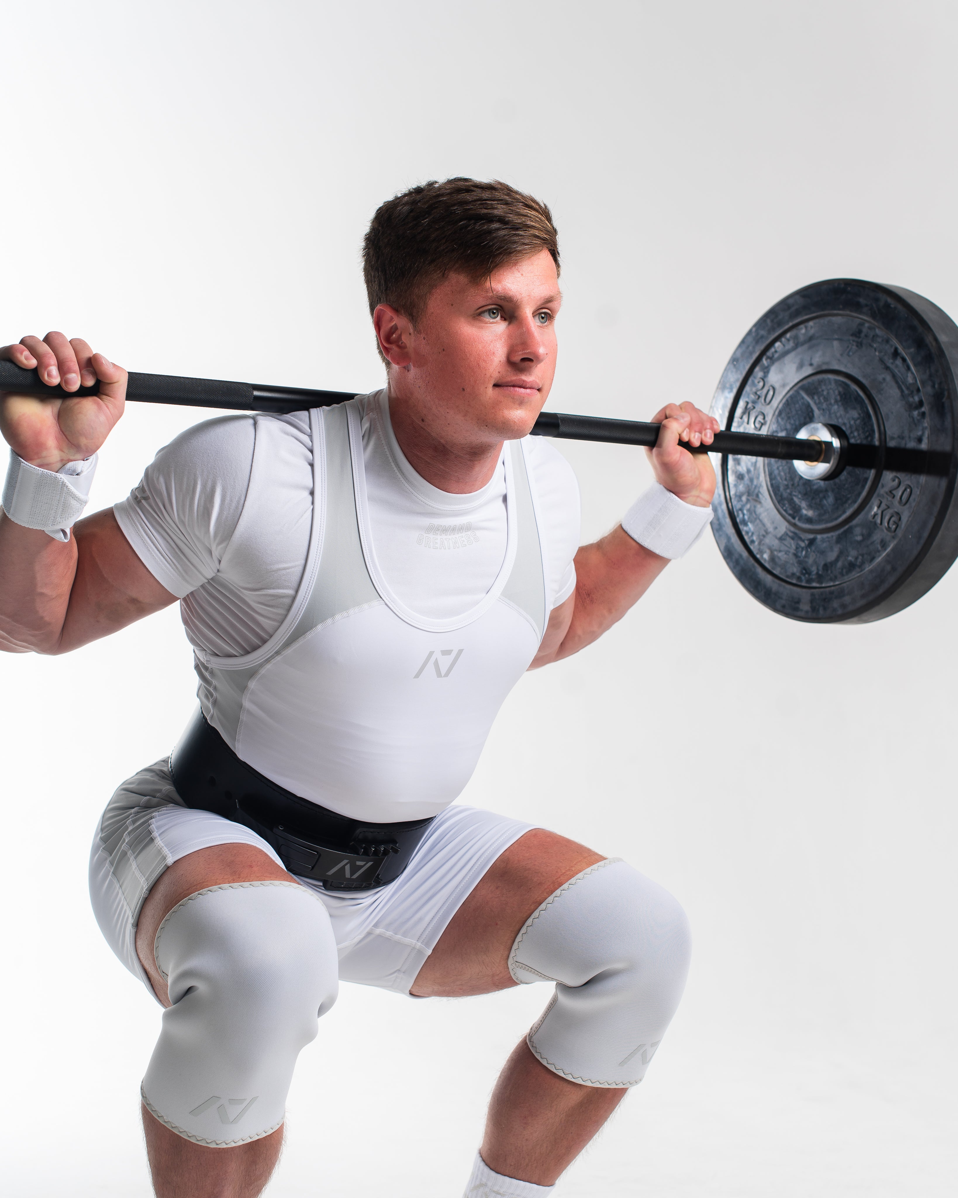 Man lifting in polar meet kit with a barbell with weights on a white background