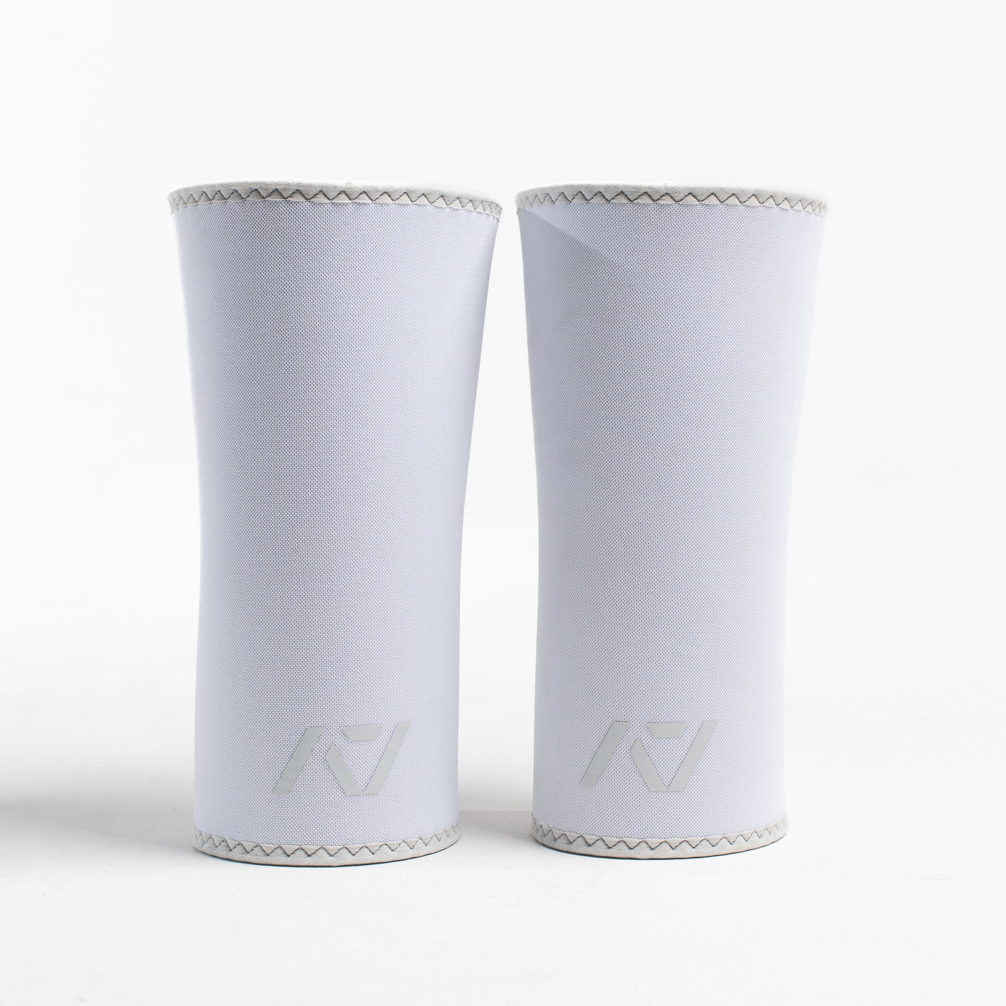 A pair of white neoprene knee sleeves with an hourglass-shaped center fit, displayed against a white background.