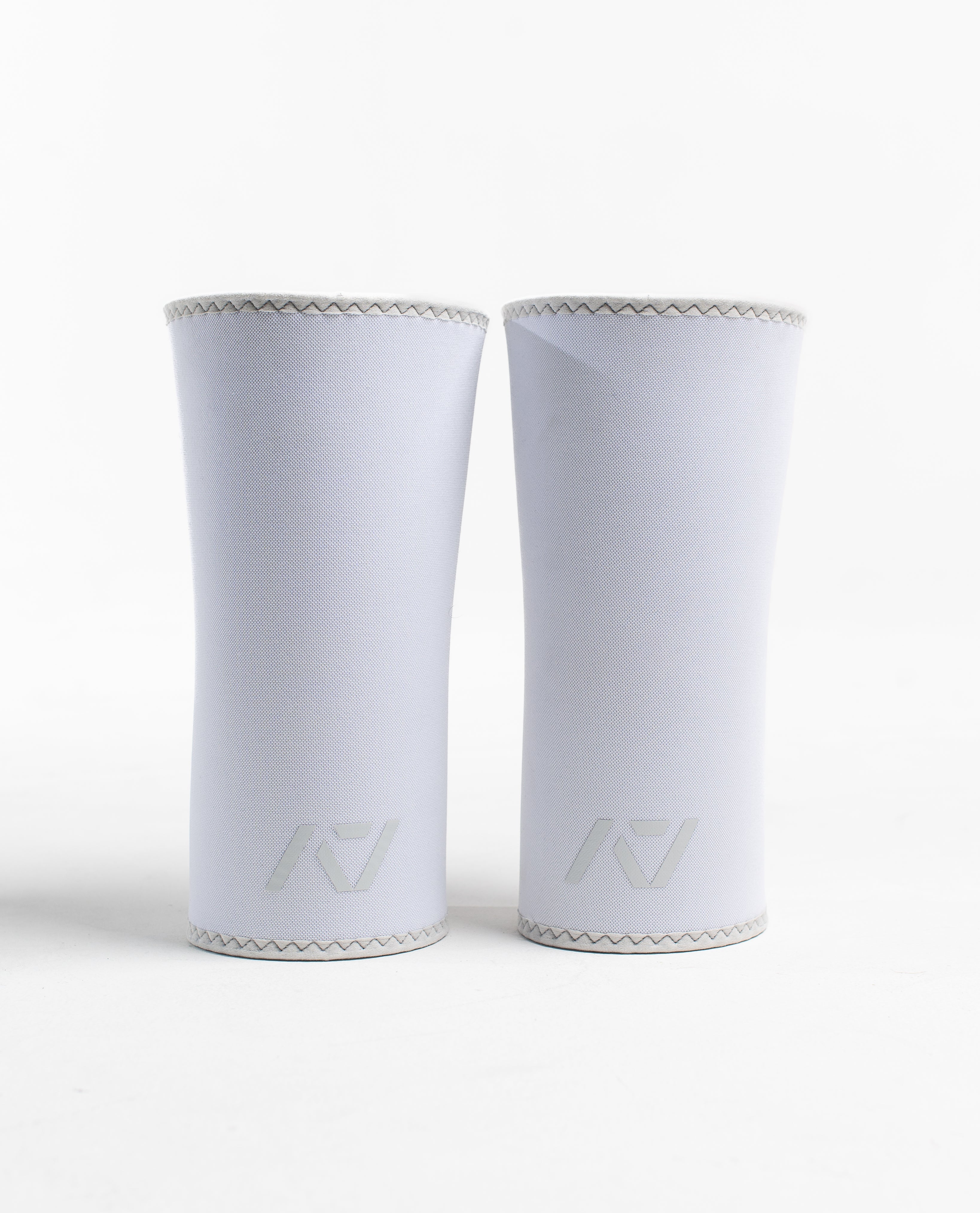 A pair of white neoprene knee sleeves with an hourglass-shaped center fit, displayed against a white background.