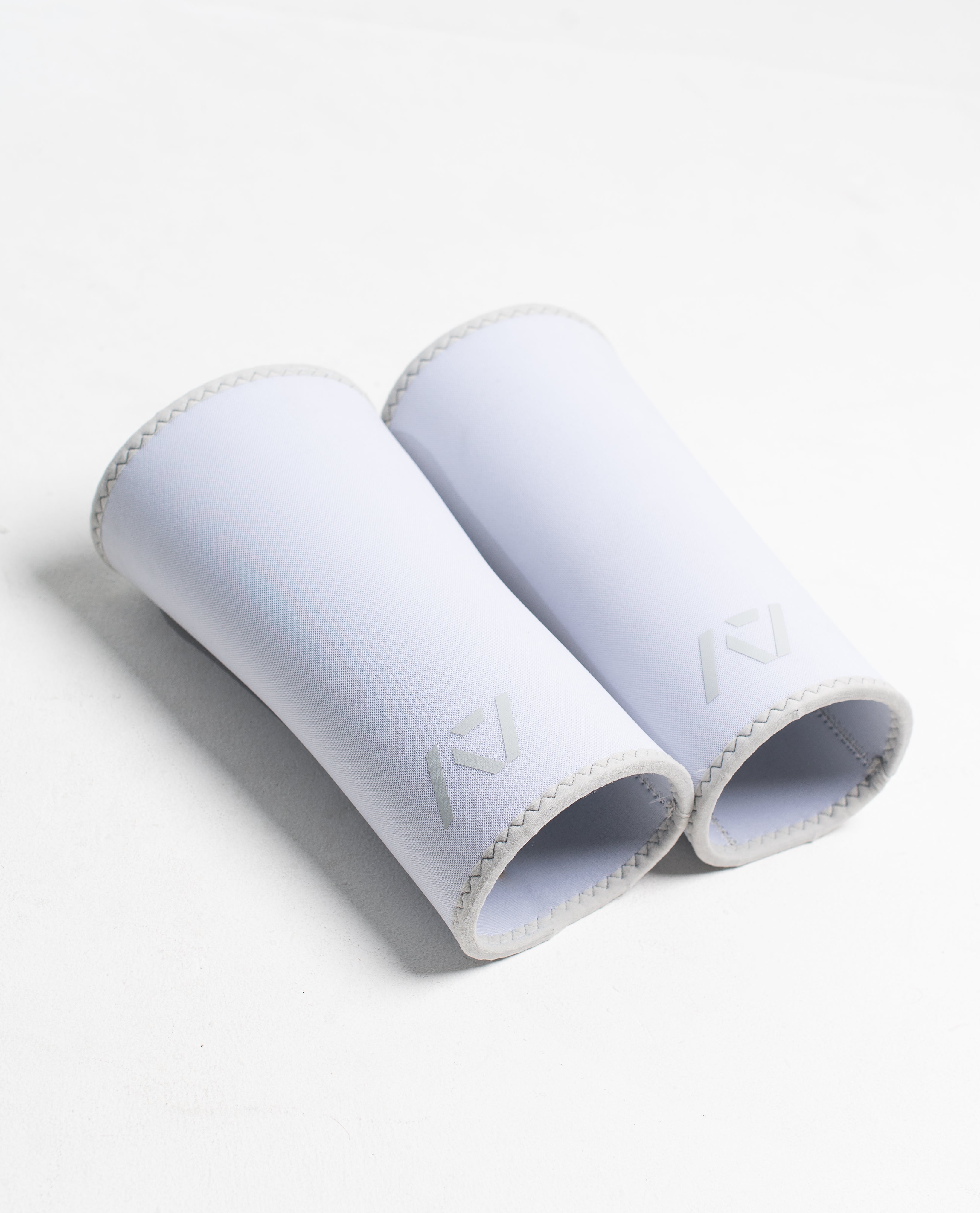 Pair of white hourglass knee sleeves on a white background