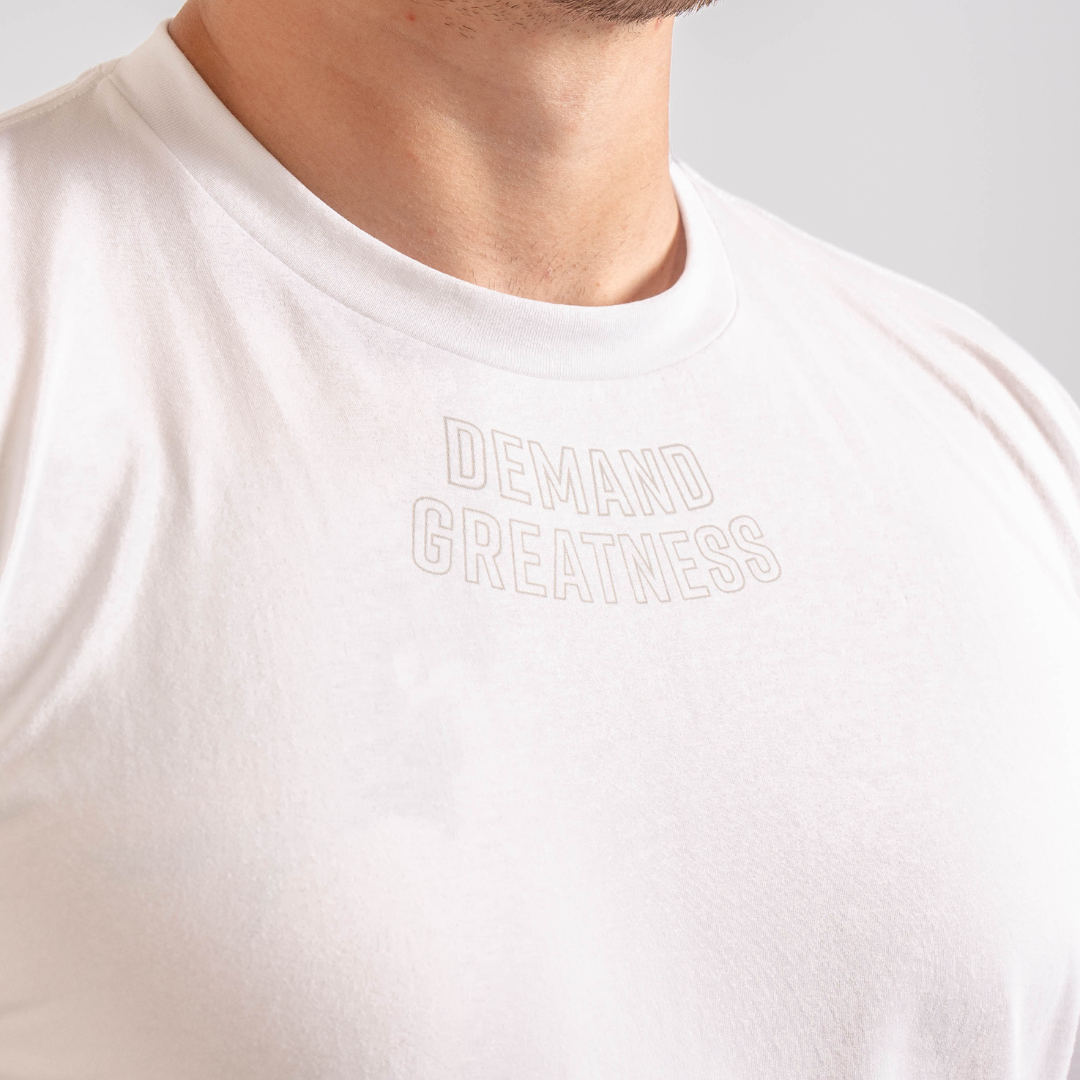 Close up of Demand Greatness text on the top of the chest on the front of the meet shirt