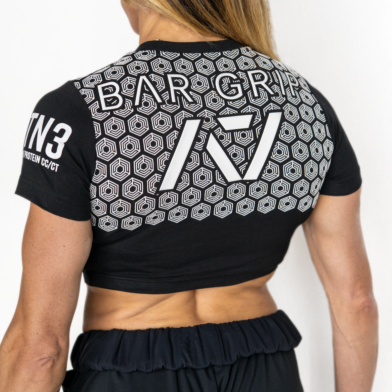 Person wearing a black sports outfit with bar grip and branding on a white background