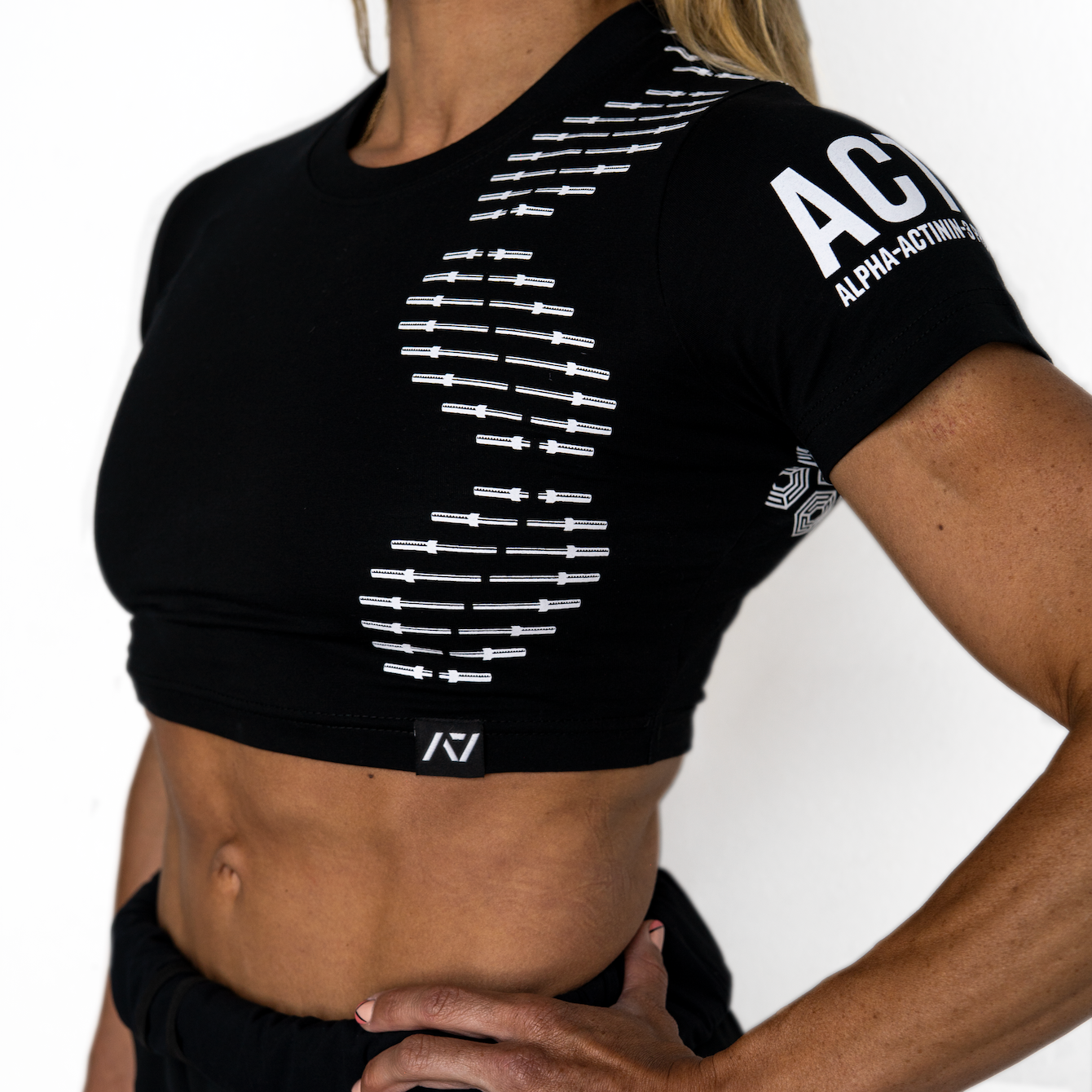 Person wearing a black athletic crop top with branding on a white background