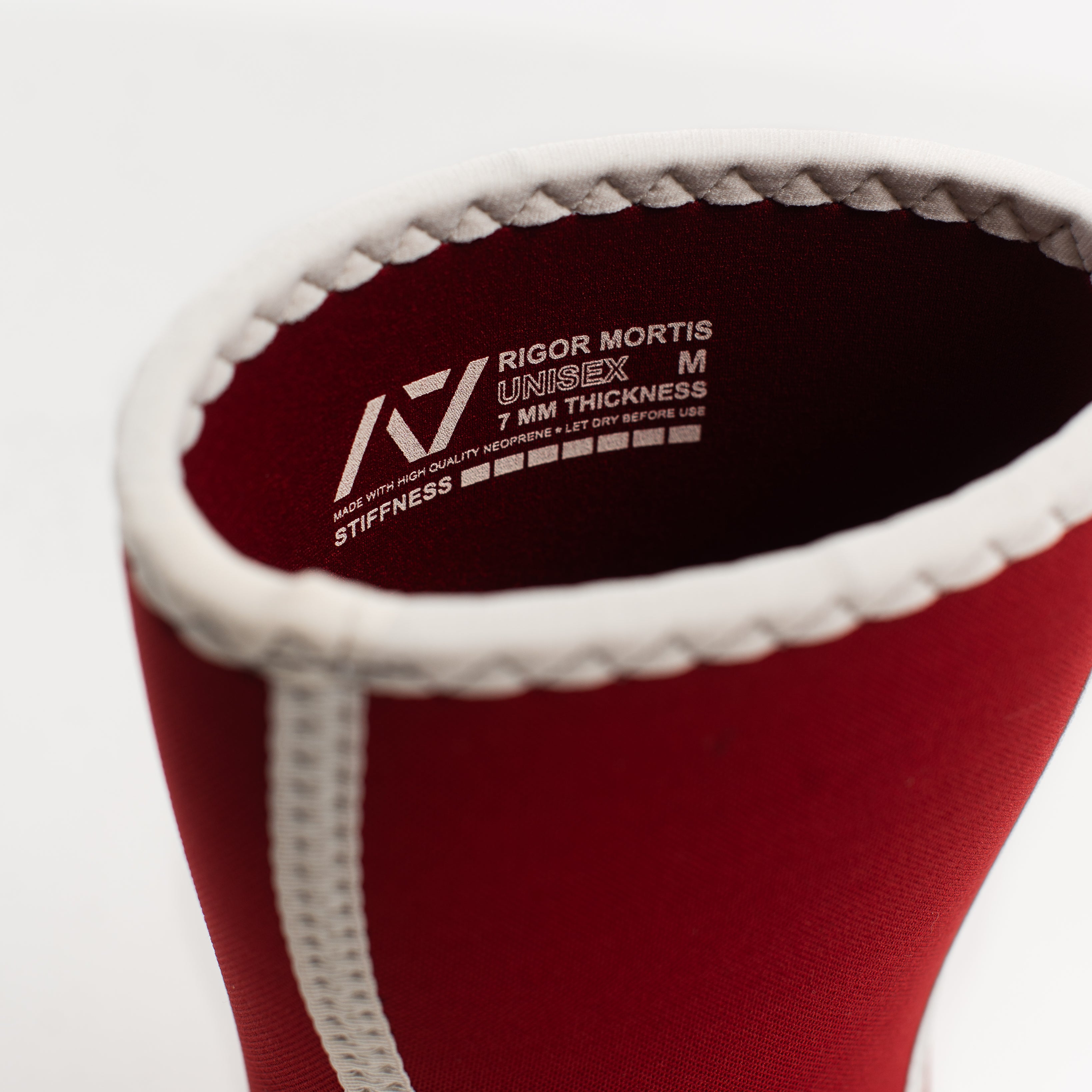 Red knee sleeve with red interior and branding text with sizing and stiffness level