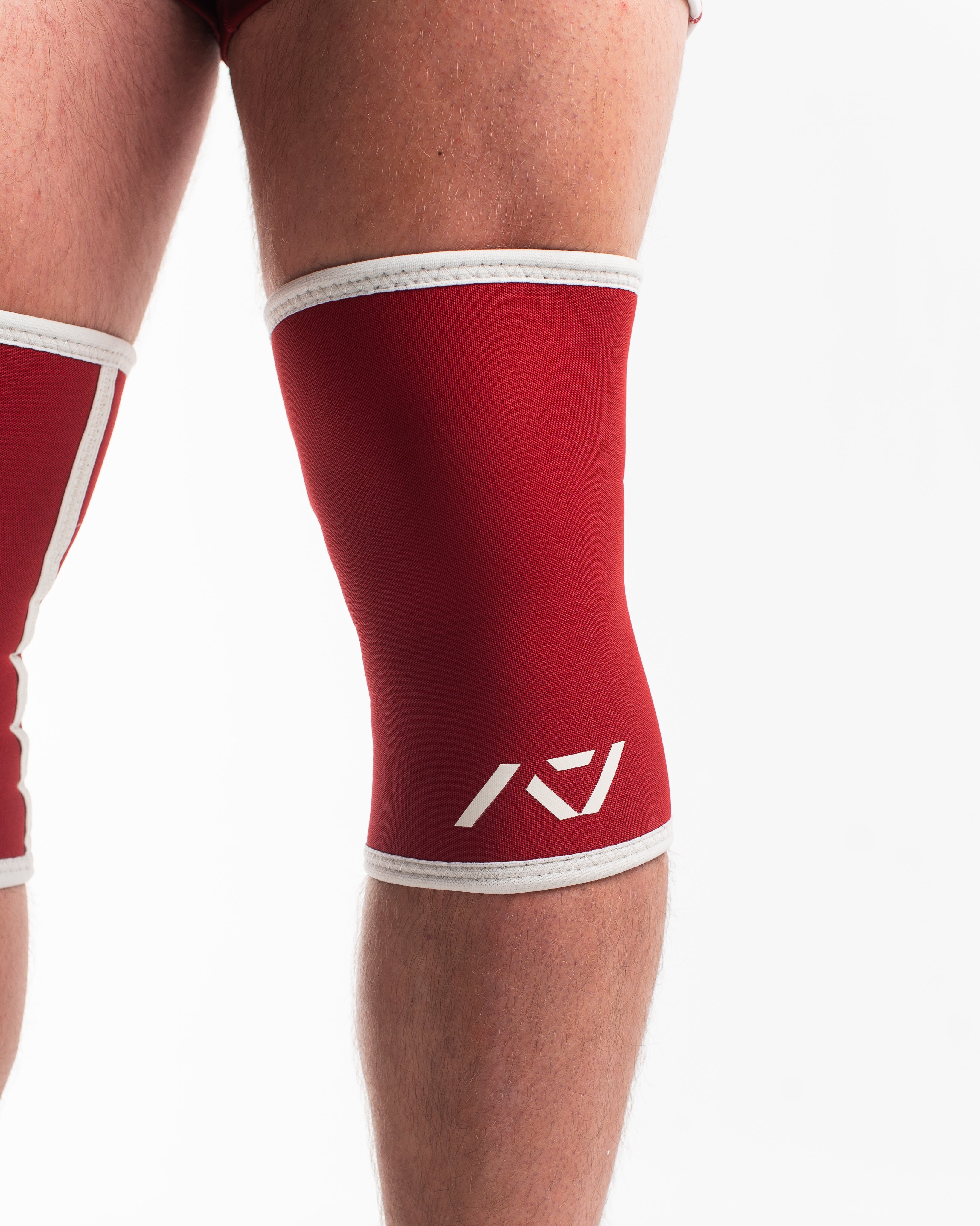 Red knee sleeve with white logo on a plain background
