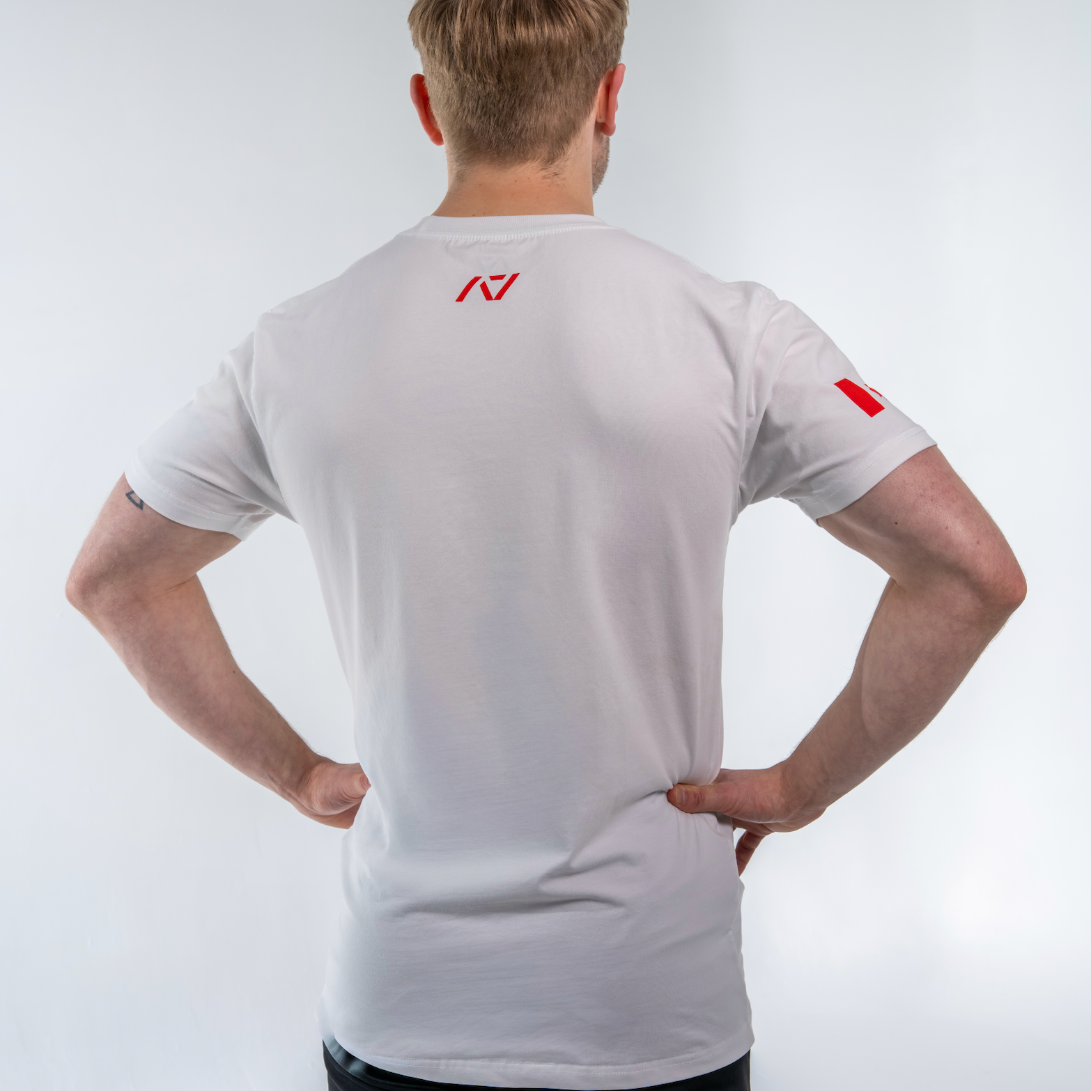 Person wearing a white shirt with a red logo on a light gray background