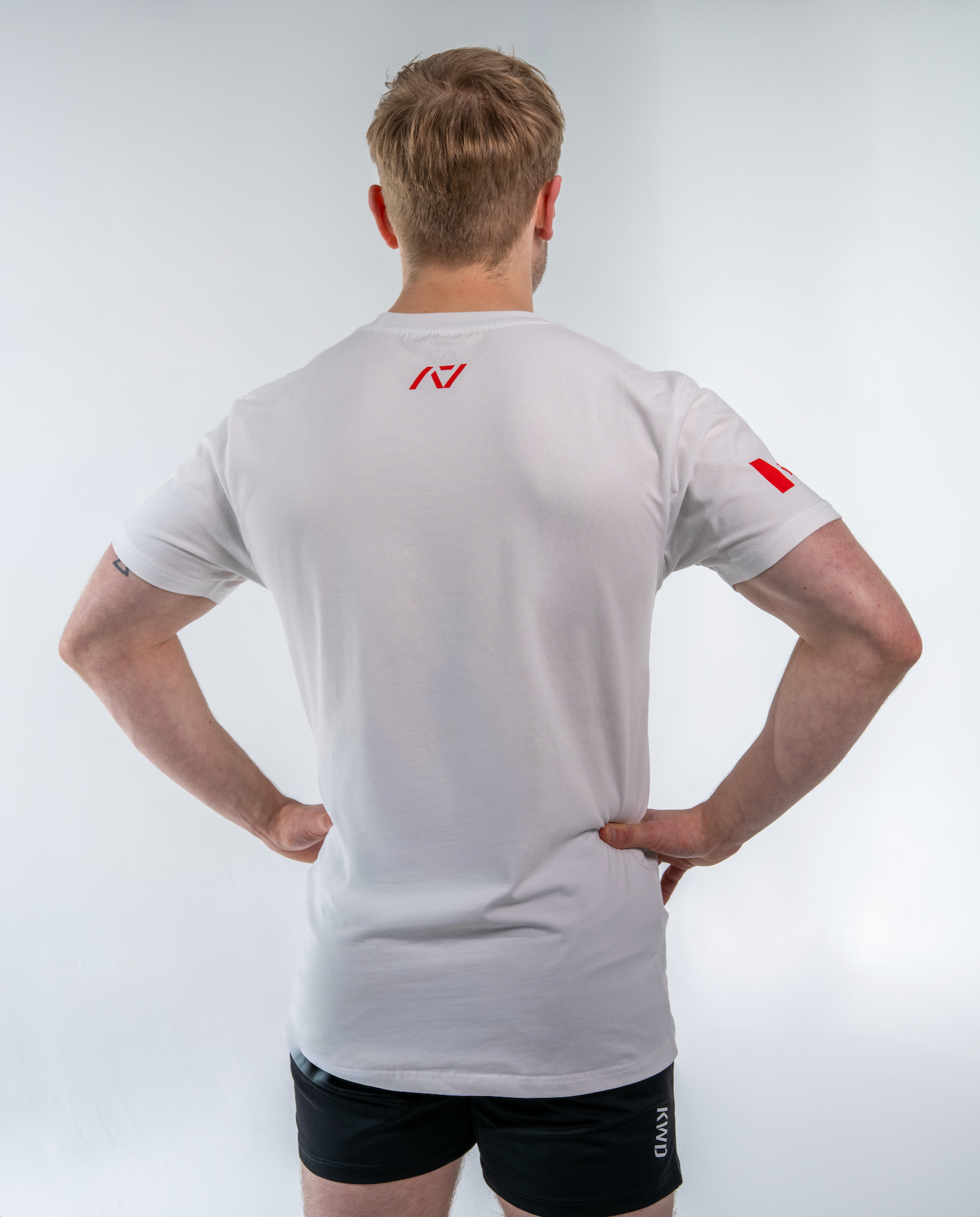 Person wearing a white shirt with a red logo on a light gray background