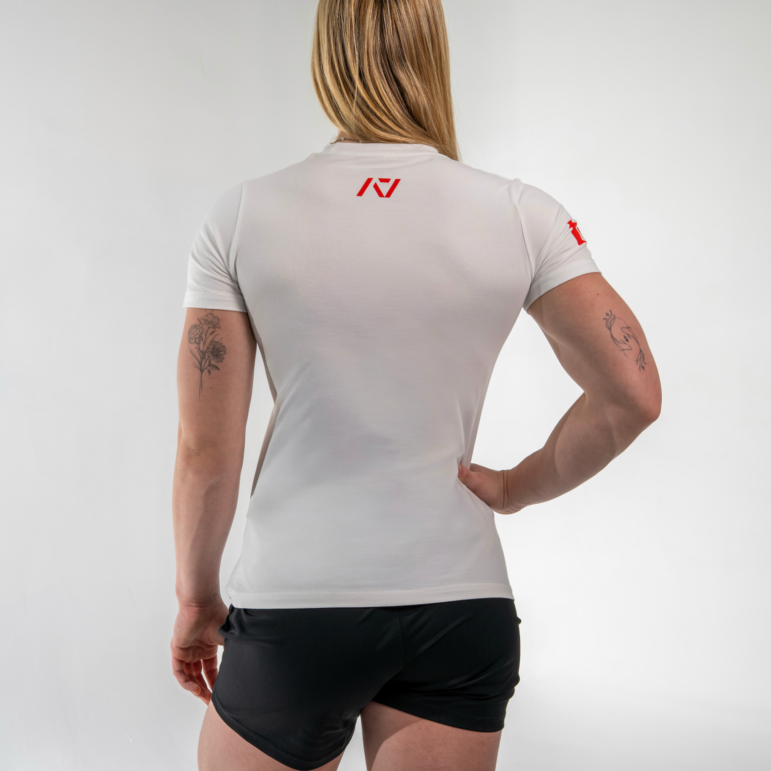 Person wearing a white athletic shirt with a logo on the back, standing against a plain background