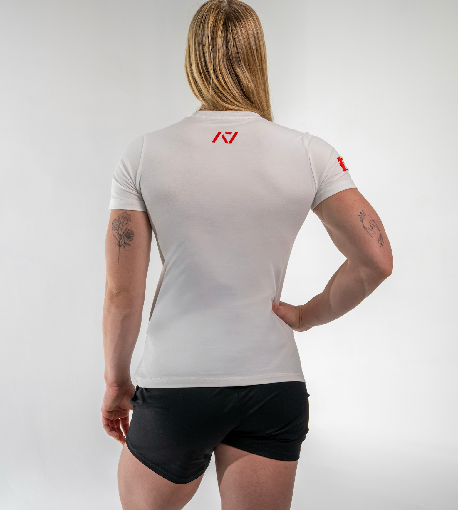 Person wearing a white athletic shirt with a logo on the back, standing against a plain background