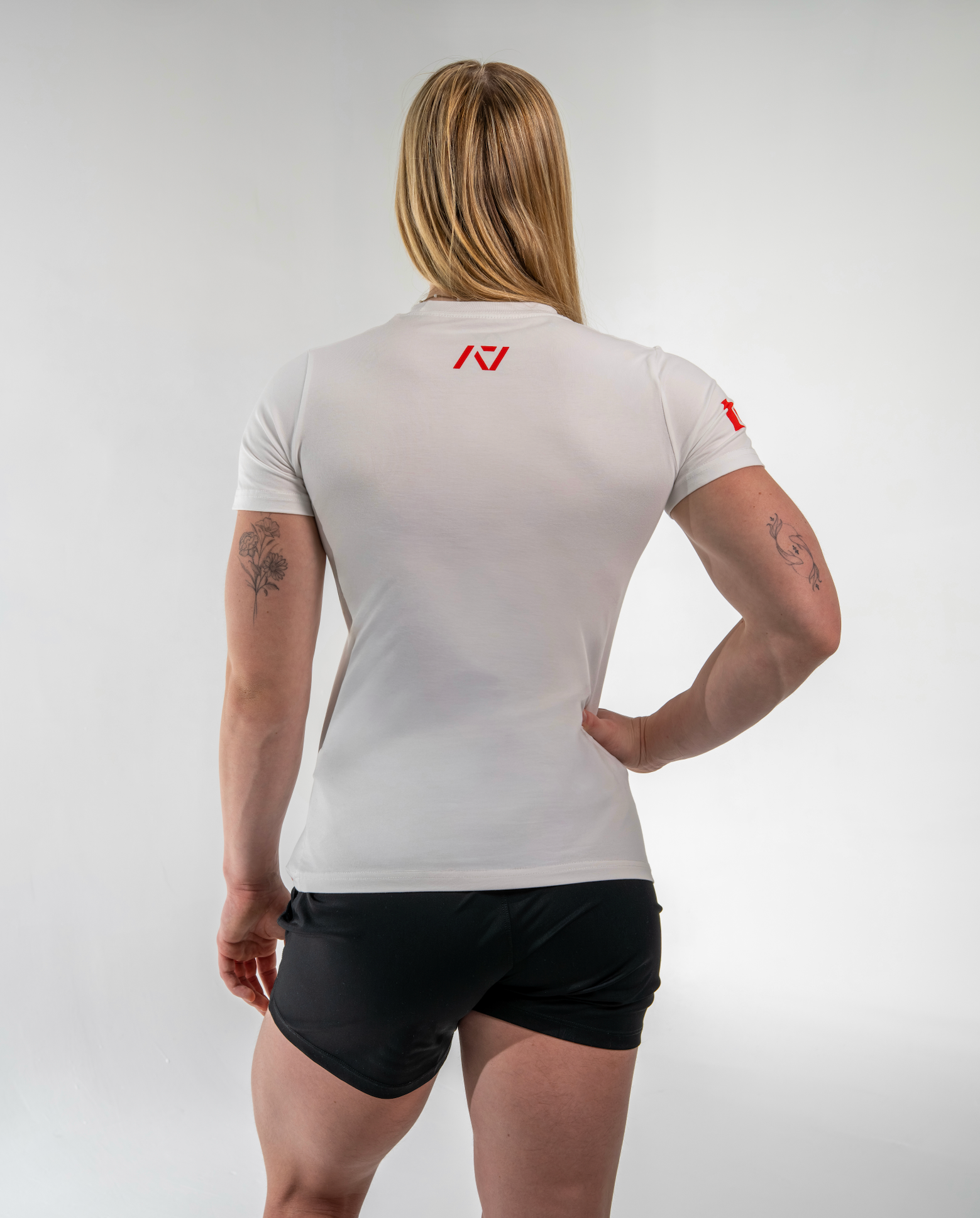 Person wearing a white athletic shirt with a logo on the back, standing against a plain background