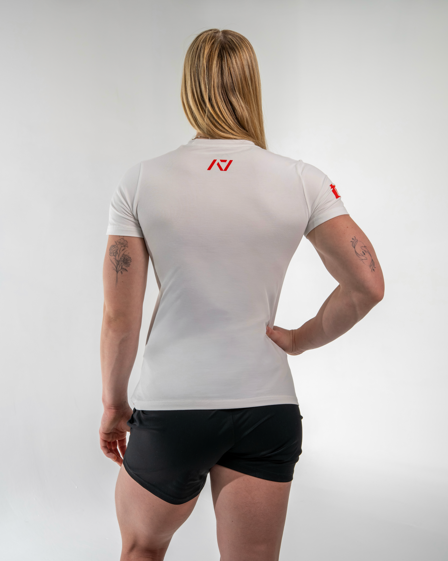 Person wearing a white athletic shirt with a logo on the back, standing against a plain background