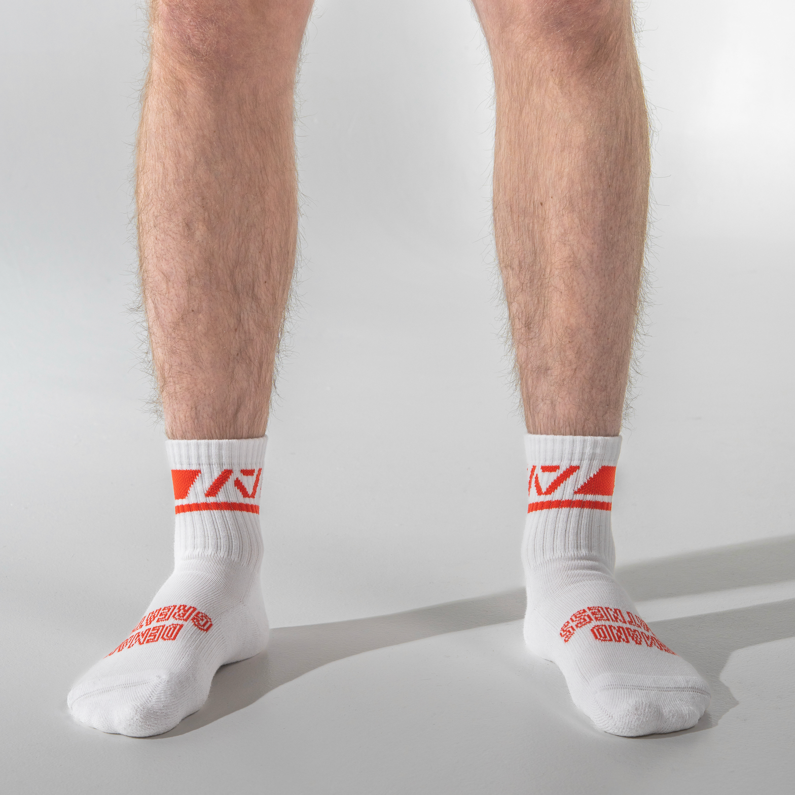 White socks with red logo worn by a person on a light gray background