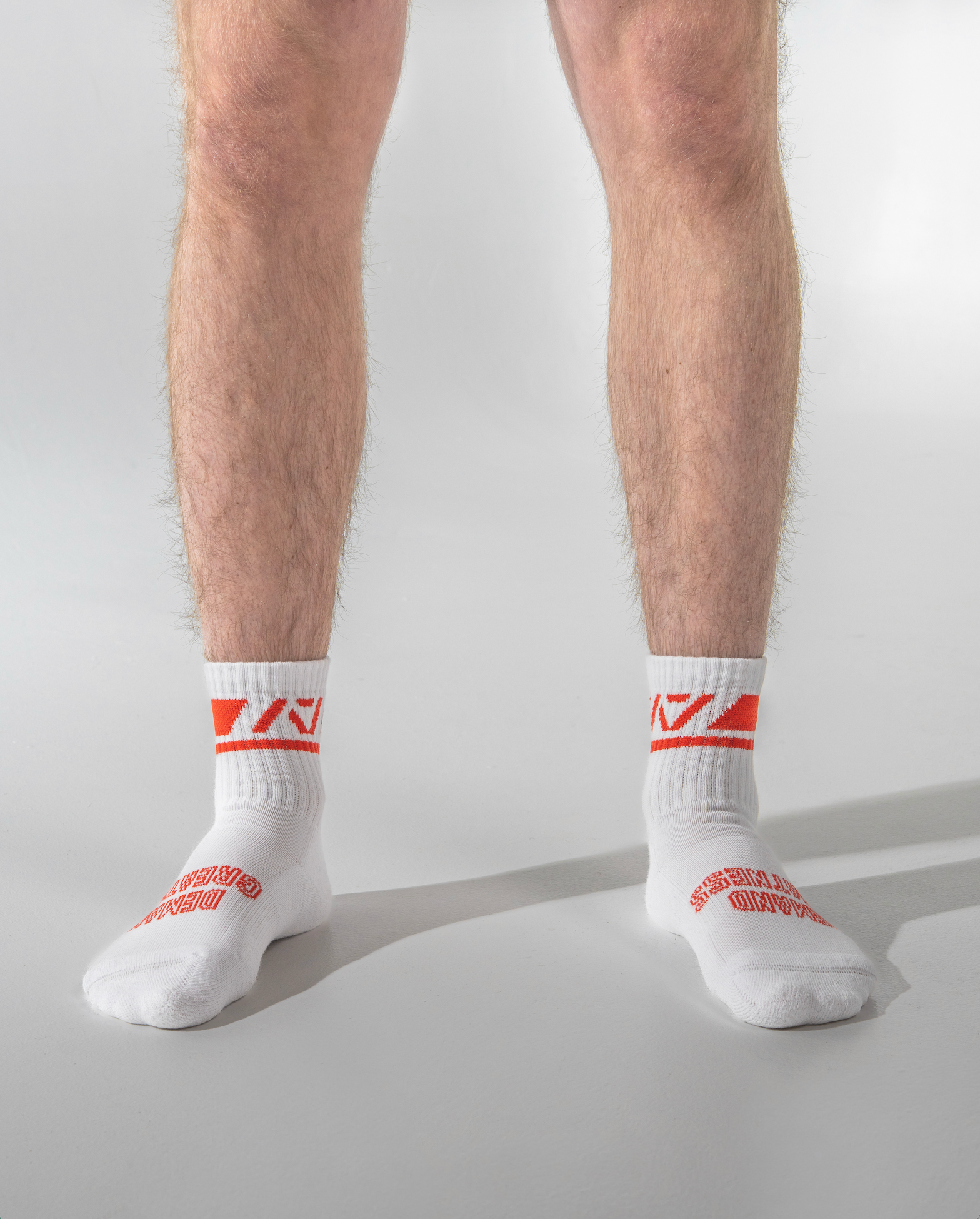 White socks with red logo worn by a person on a light gray background