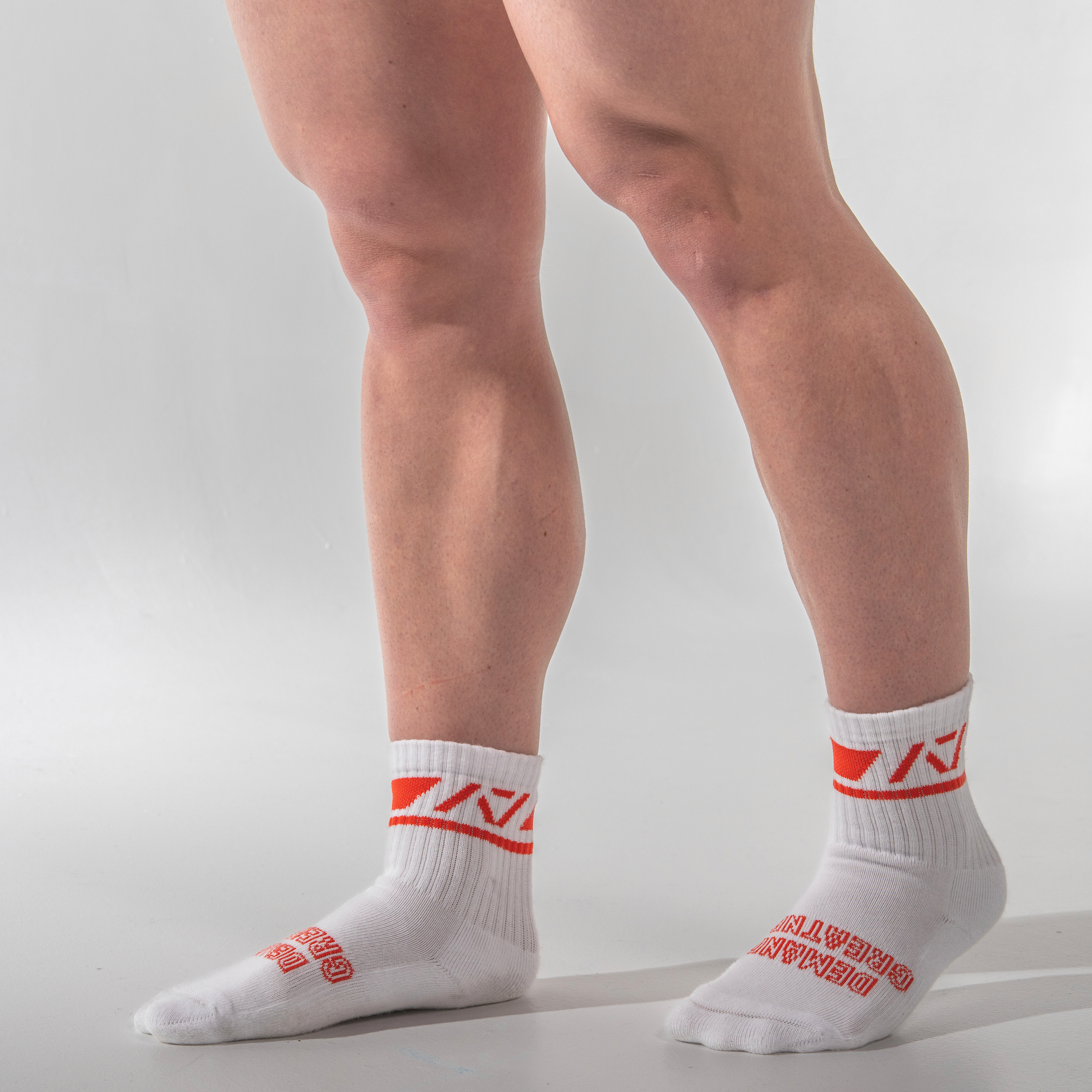 White socks with red logo worn by a person on a light gray background