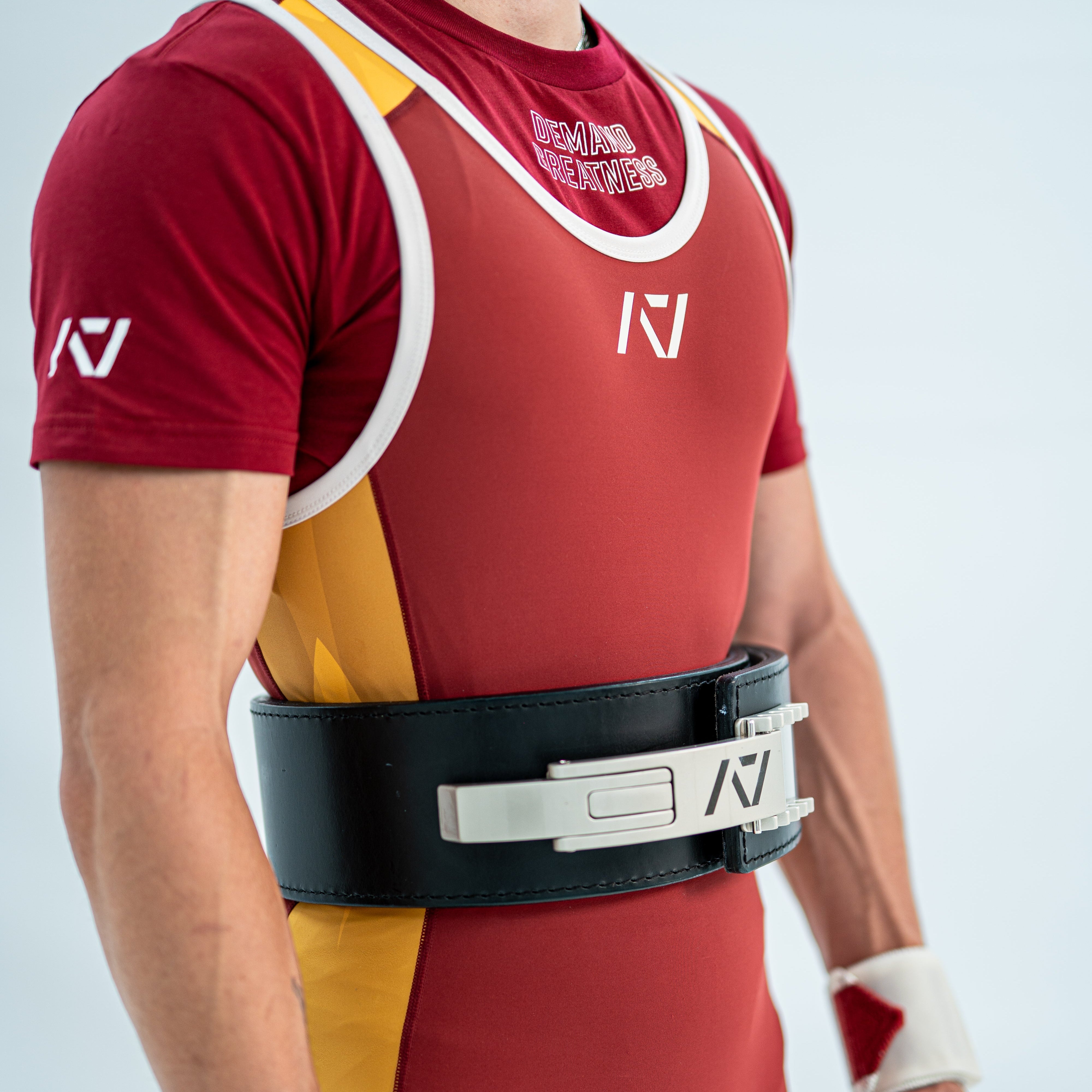Male Model wearing a red and yellow powerlifting singlet with white accents on a light gray background