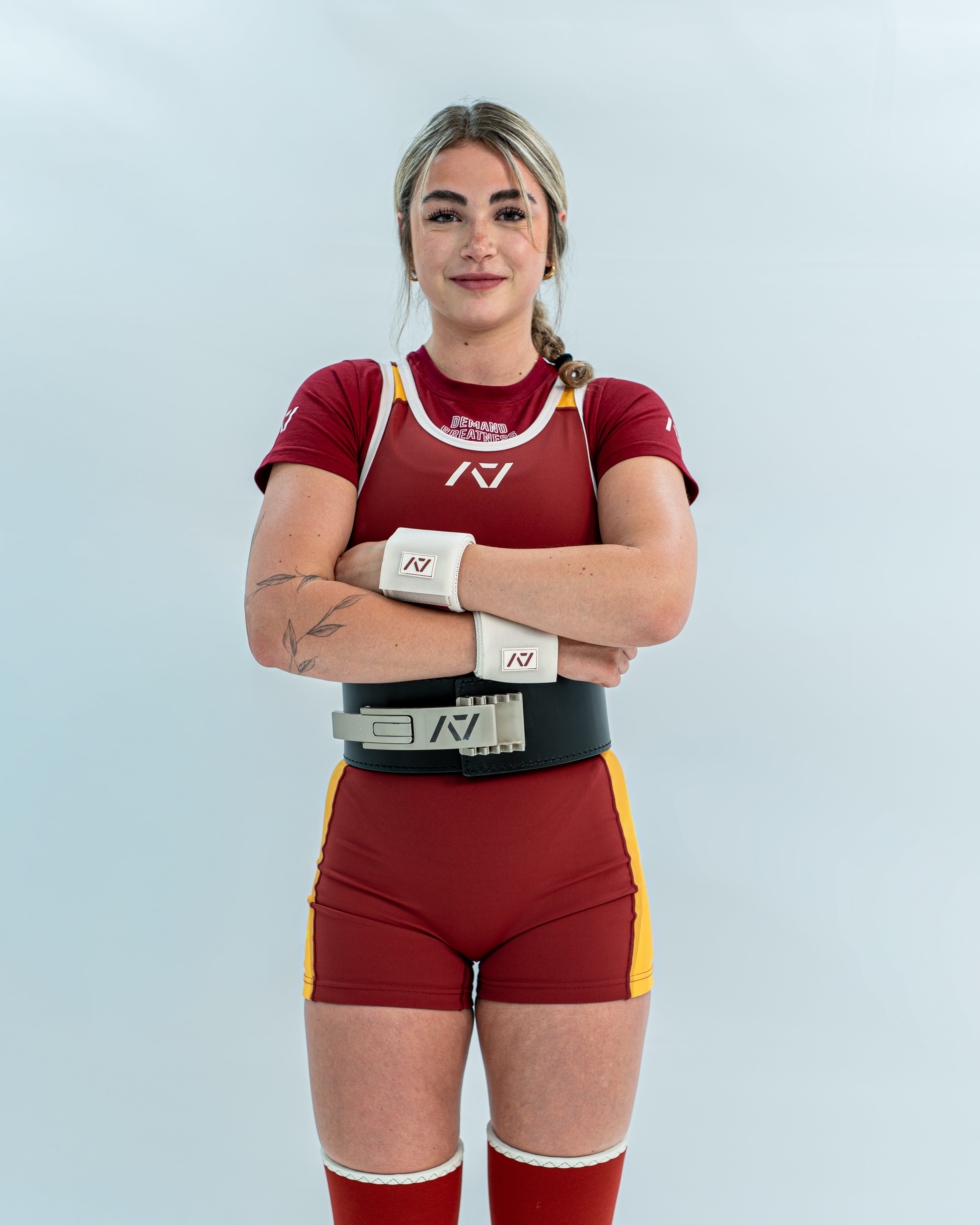Female wearing a red and yellow rausch singlet with a white background