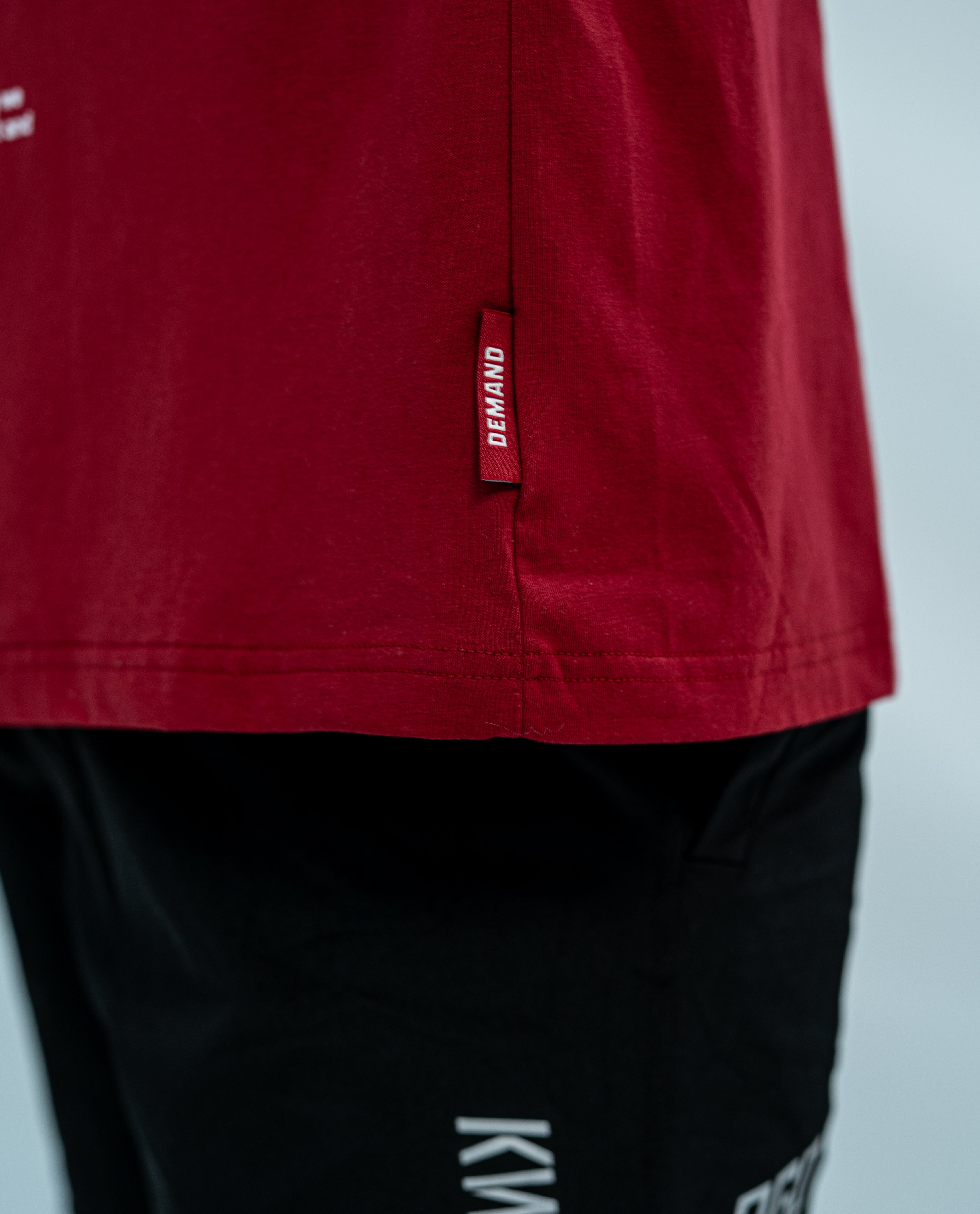 Red Over-fit Unisex shirt with a brand hem tag and featured with black 360Go KWD shorts with branding on a light gray background