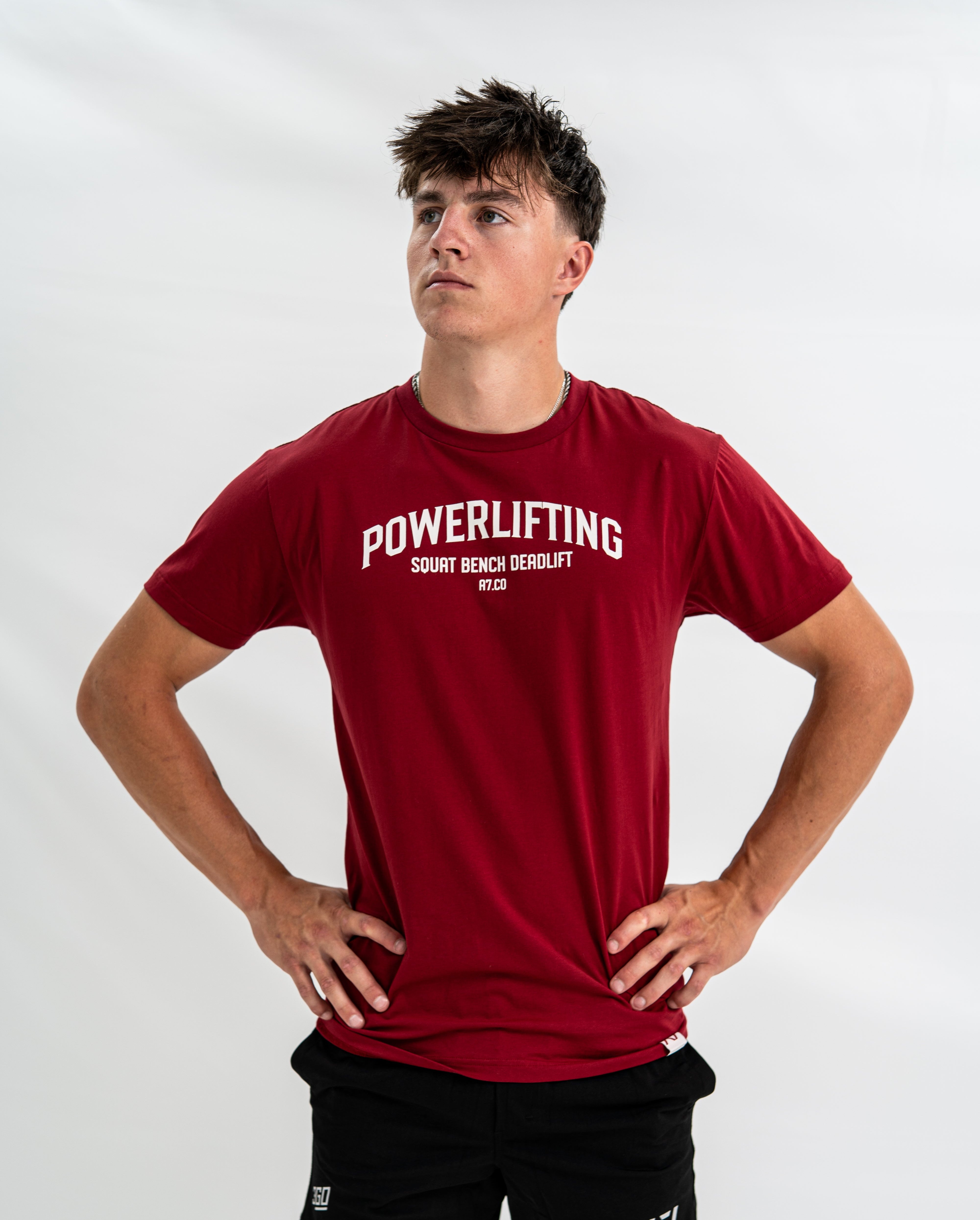 Male wearing a red 'Powerlifting' Bar Grip Shirt on a white background