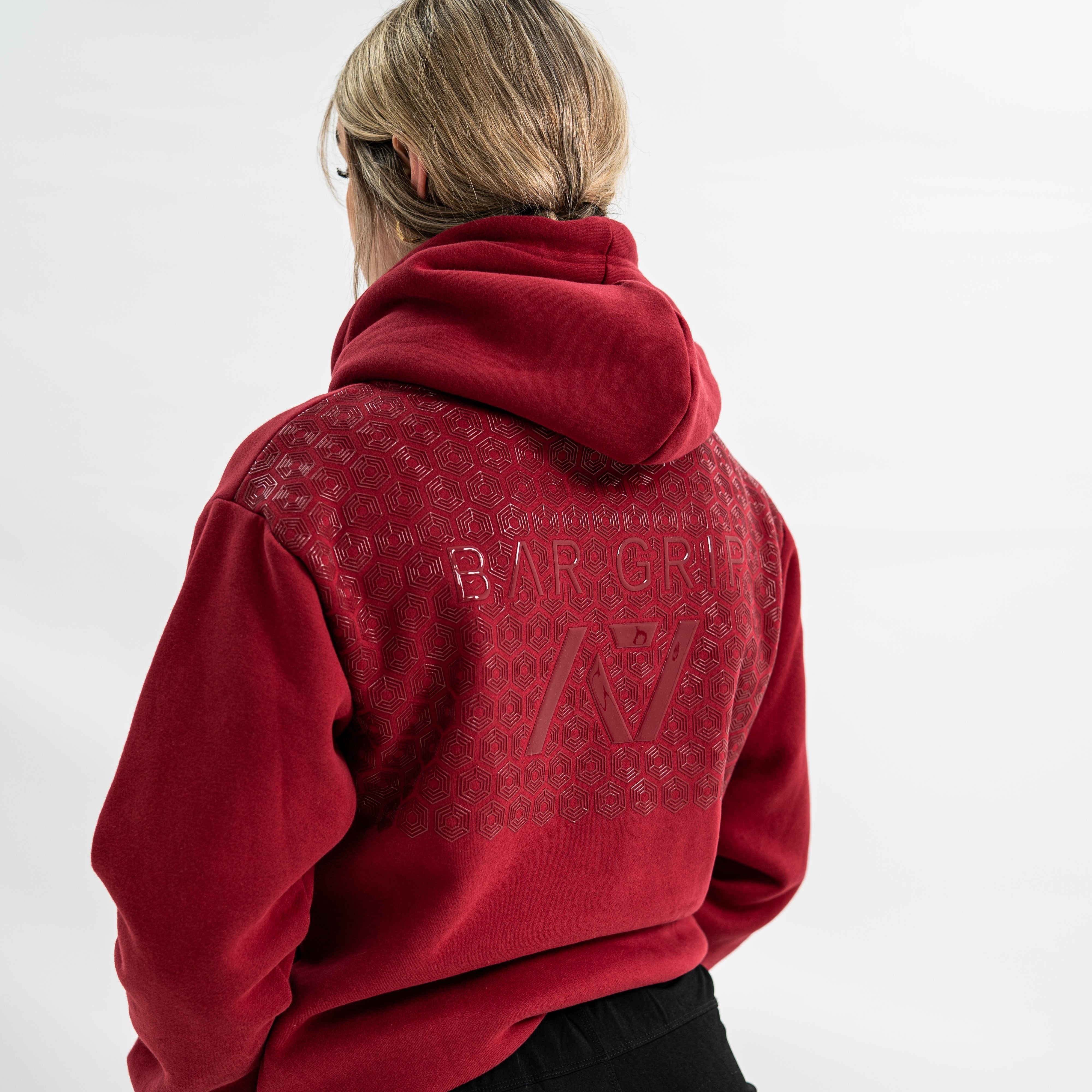 Female wearing a red hoodie with a Bar Grip Technology on the upper back against a white background