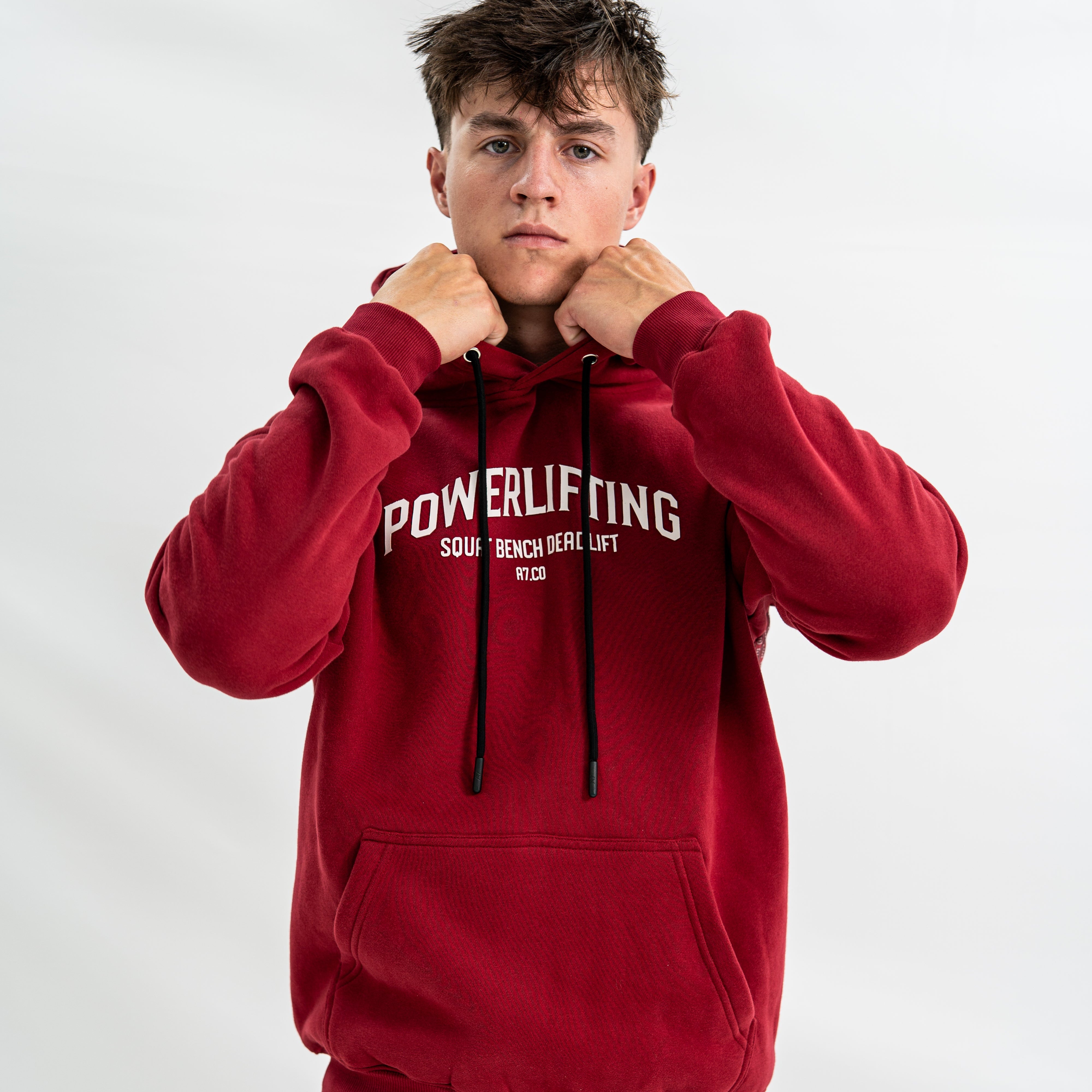 Male wearing a red 'Powerlifting' bar grip hoodie on a white background