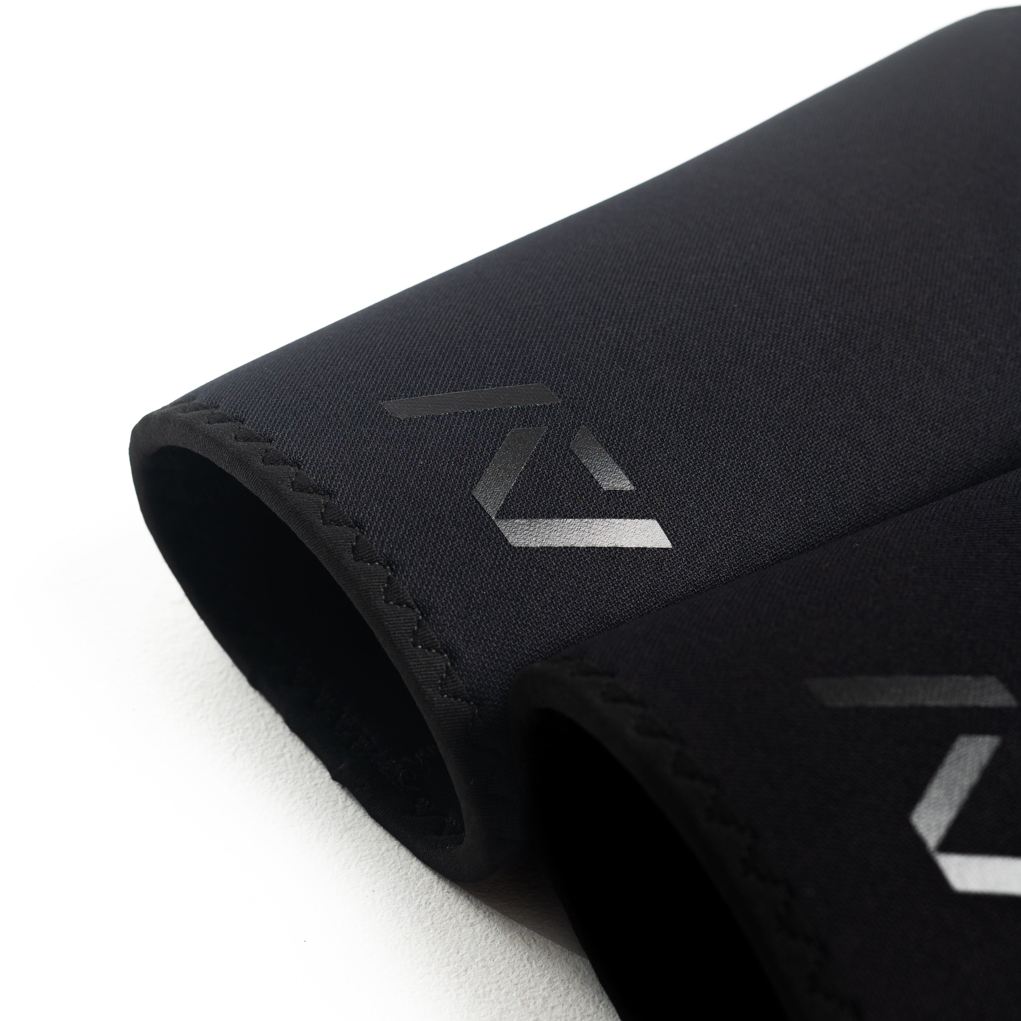 Flat lay of A7 Hourglass Knee Sleeves – Stealth pair, illustrating unisex design and sleek black finish.