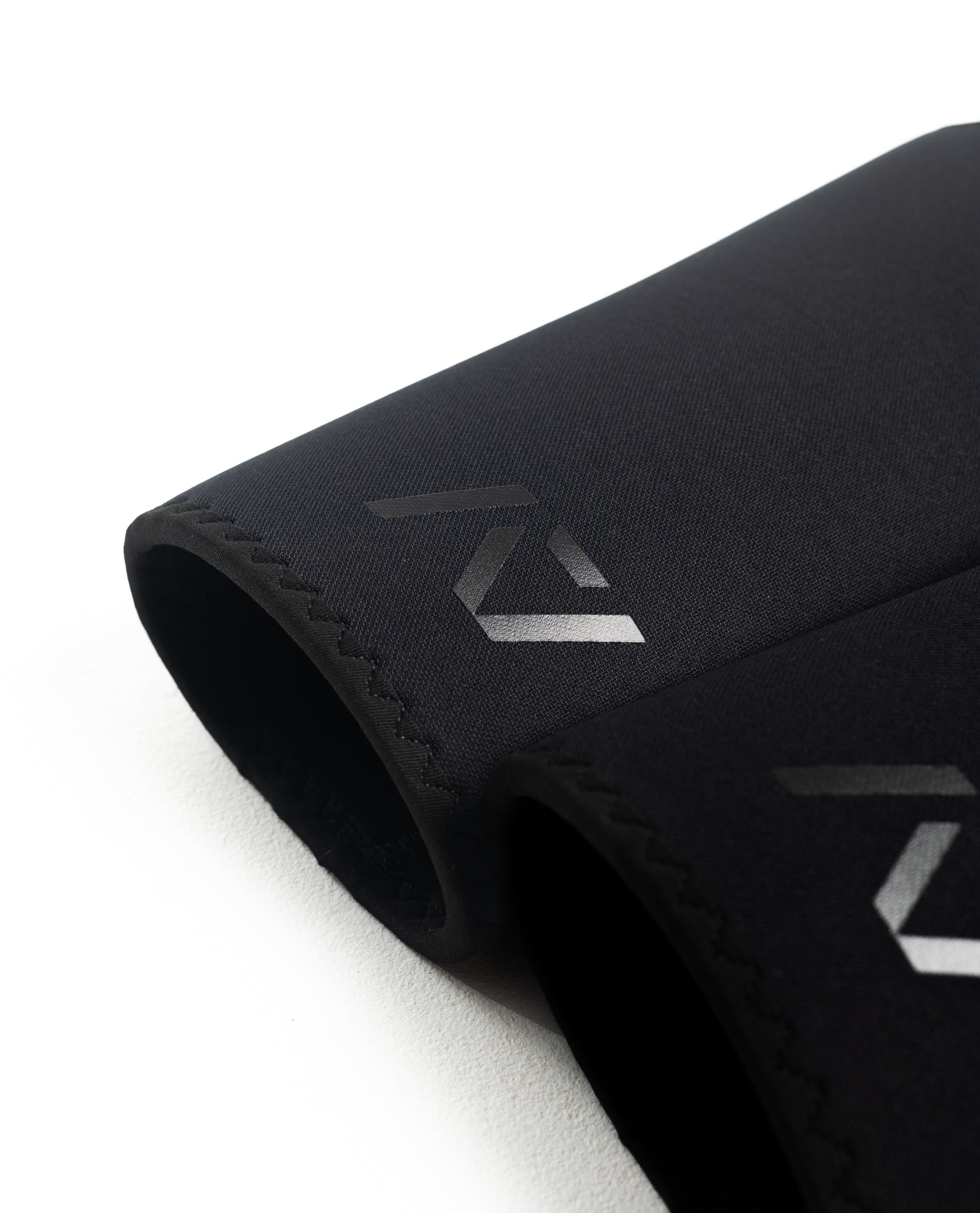 Flat lay of A7 Hourglass Knee Sleeves – Stealth pair, illustrating unisex design and sleek black finish.