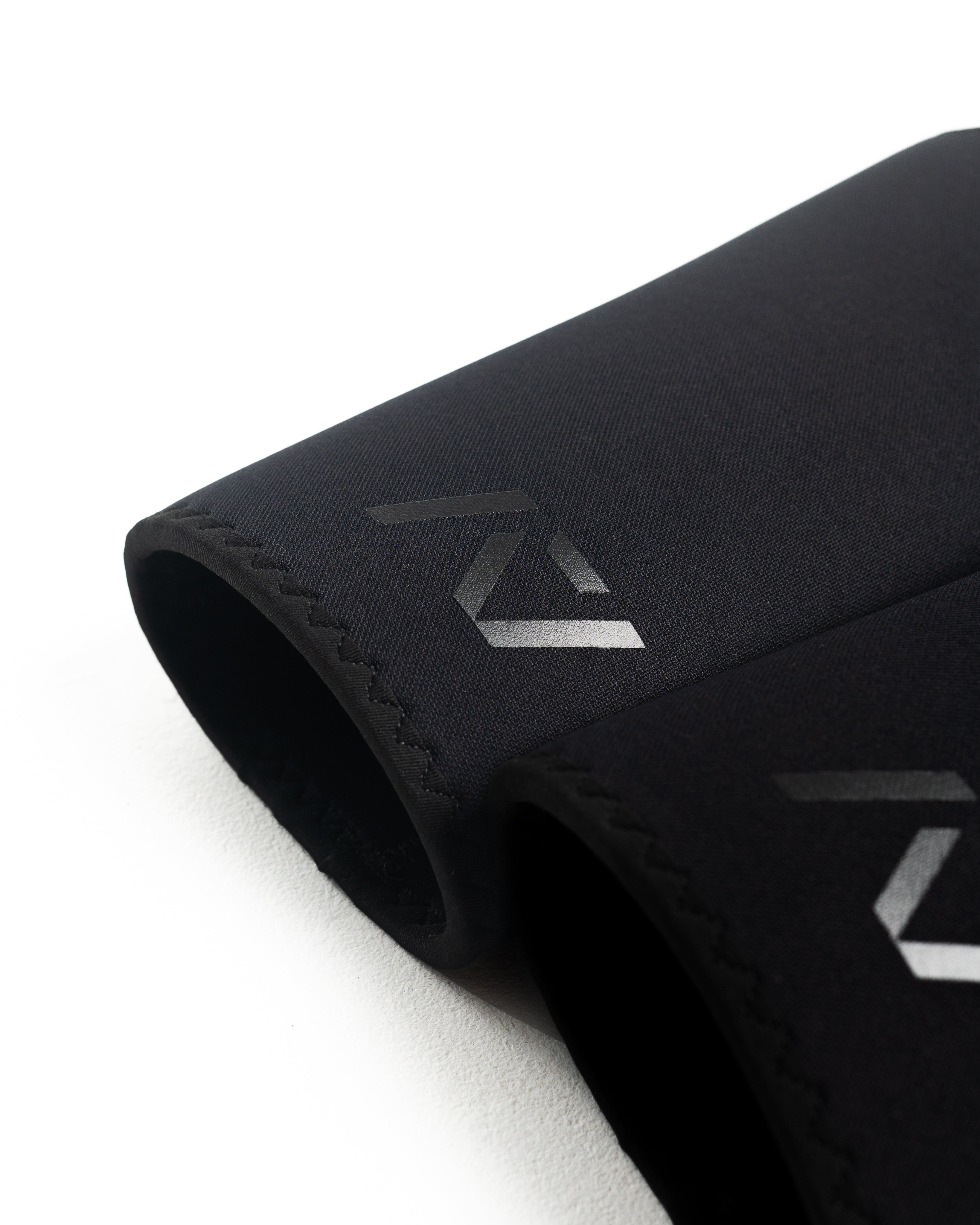 Flat lay of A7 Hourglass Knee Sleeves – Stealth pair, illustrating unisex design and sleek black finish.
