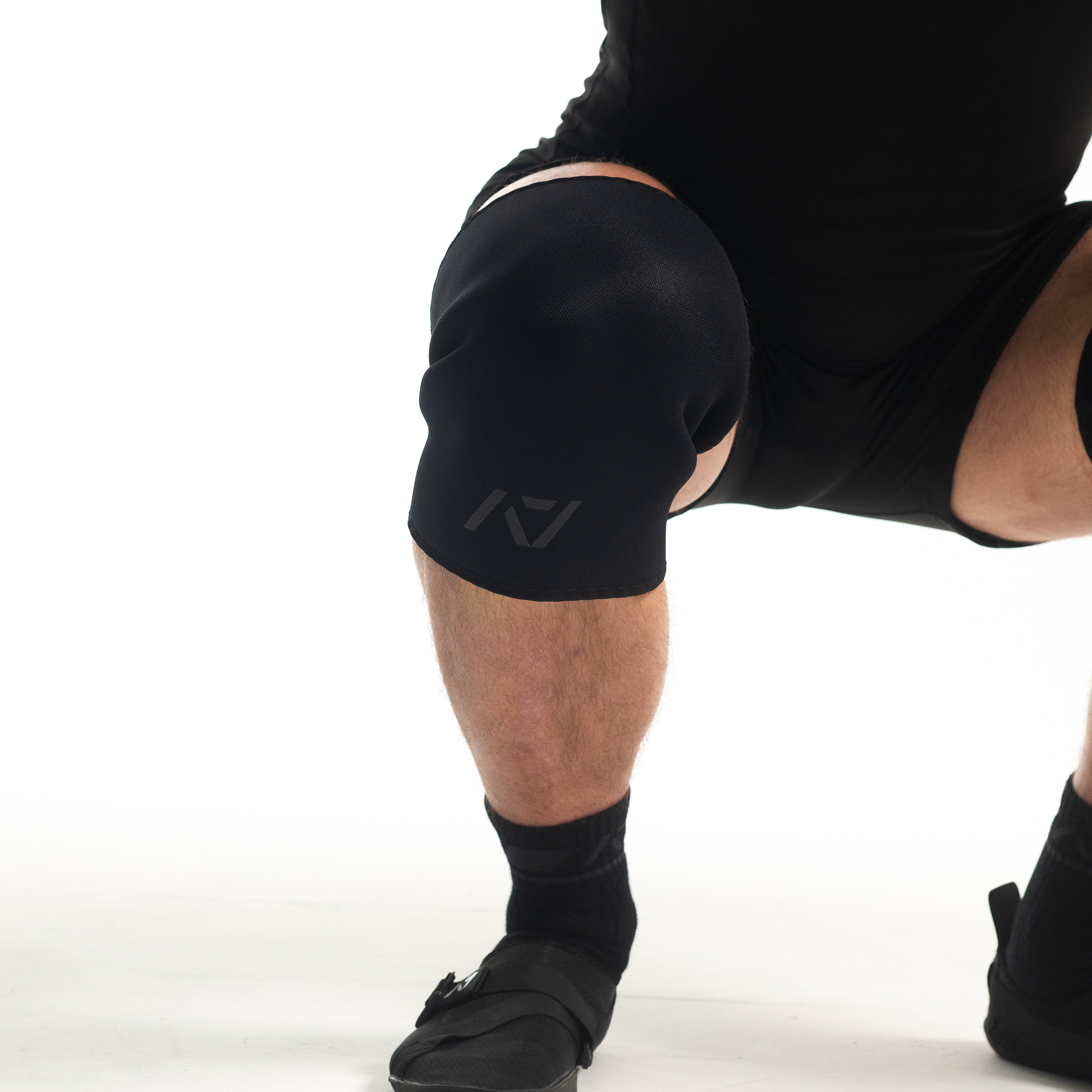 Athlete wearing A7 Hourglass Knee Sleeves – Stealth during a squat, showcasing ergonomic hourglass design for optimal knee compression.