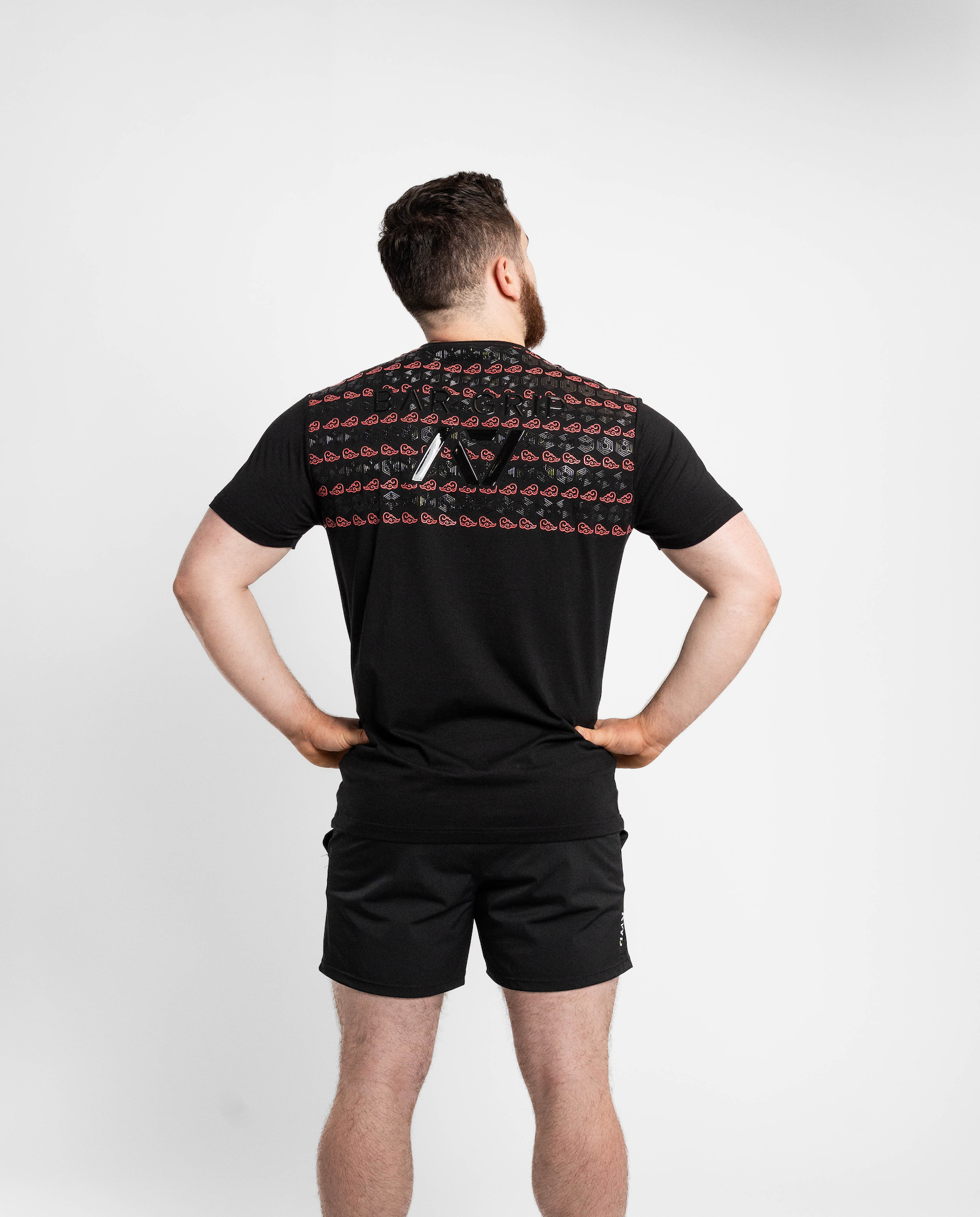 Person wearing a black t-shirt with A7 bar grip on the back and black shorts against a white background