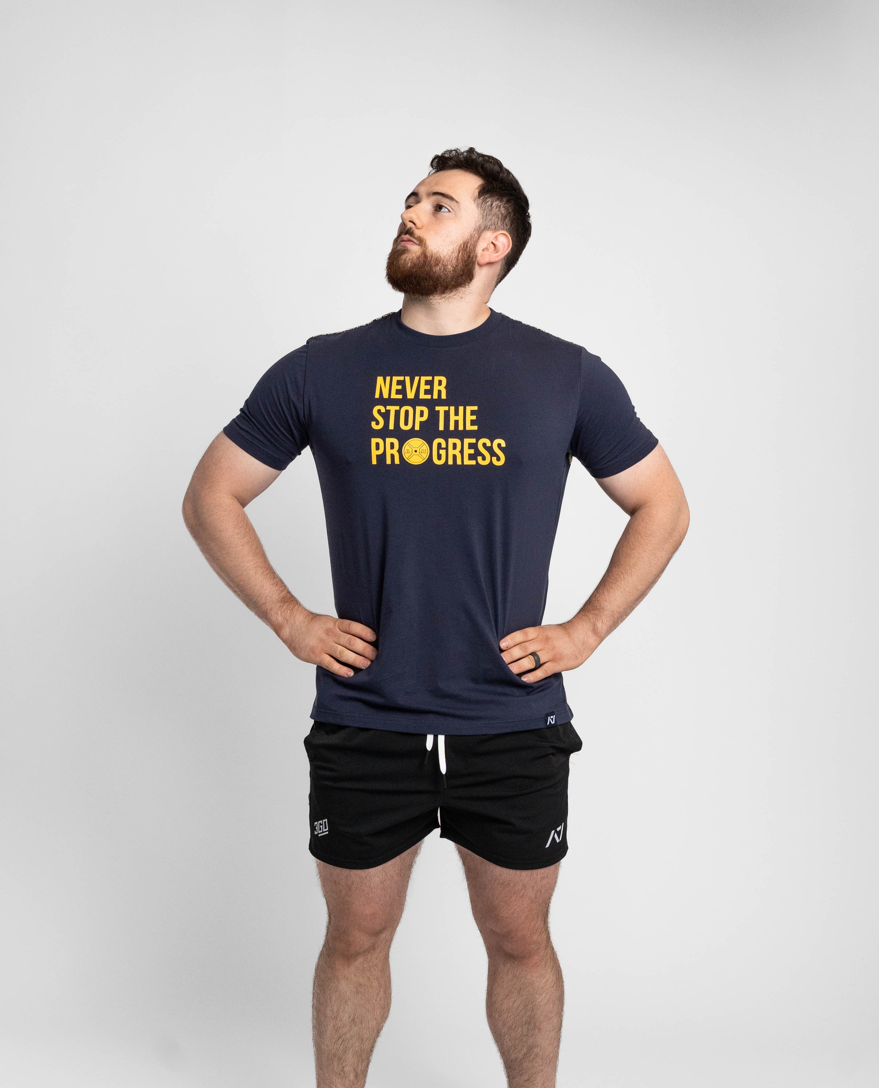 Man wearing a navy t-shirt with 'Never Stop The Progress' text on a white background
