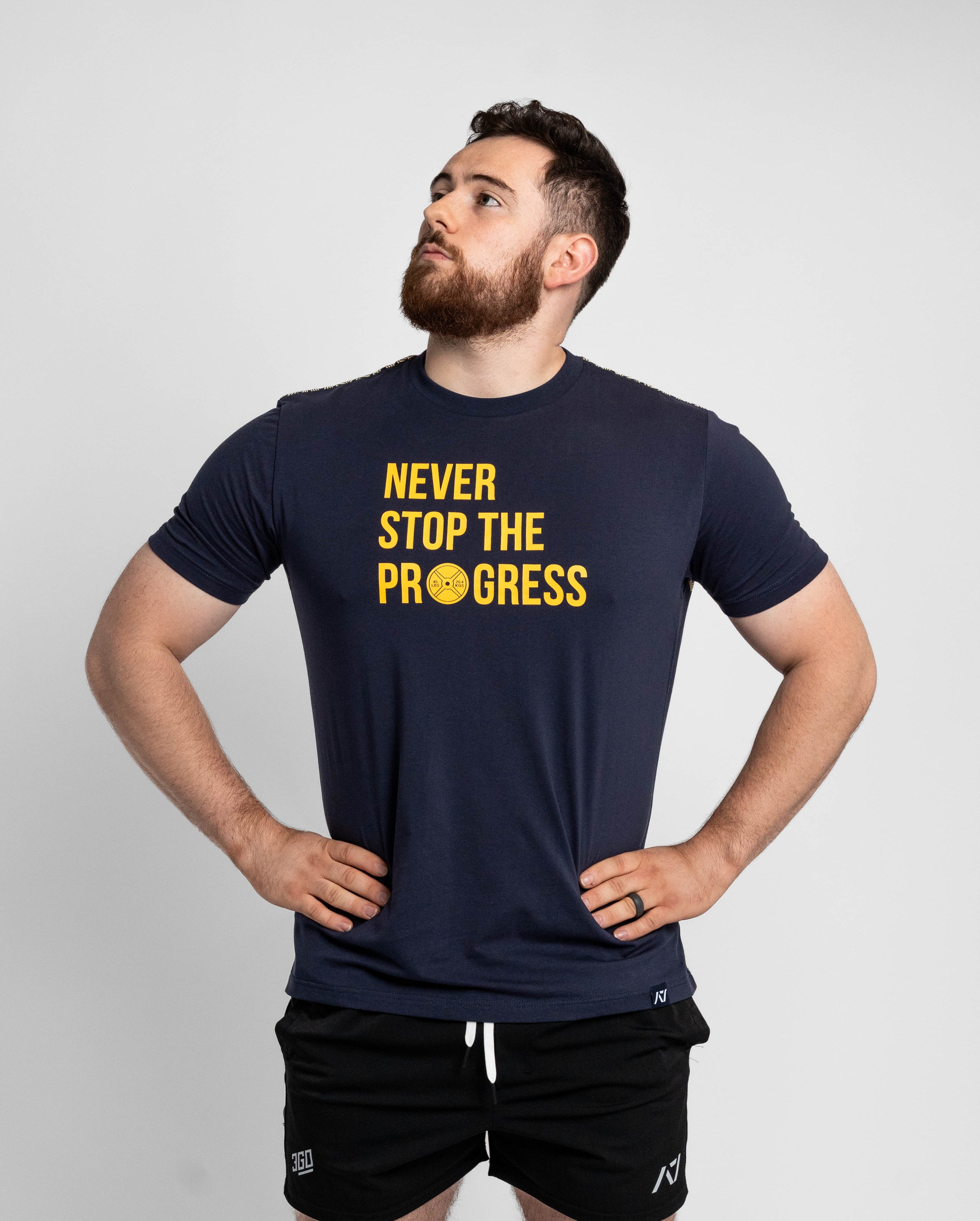 Man wearing a navy t-shirt with 'Never Stop The Progress' text on a light gray background