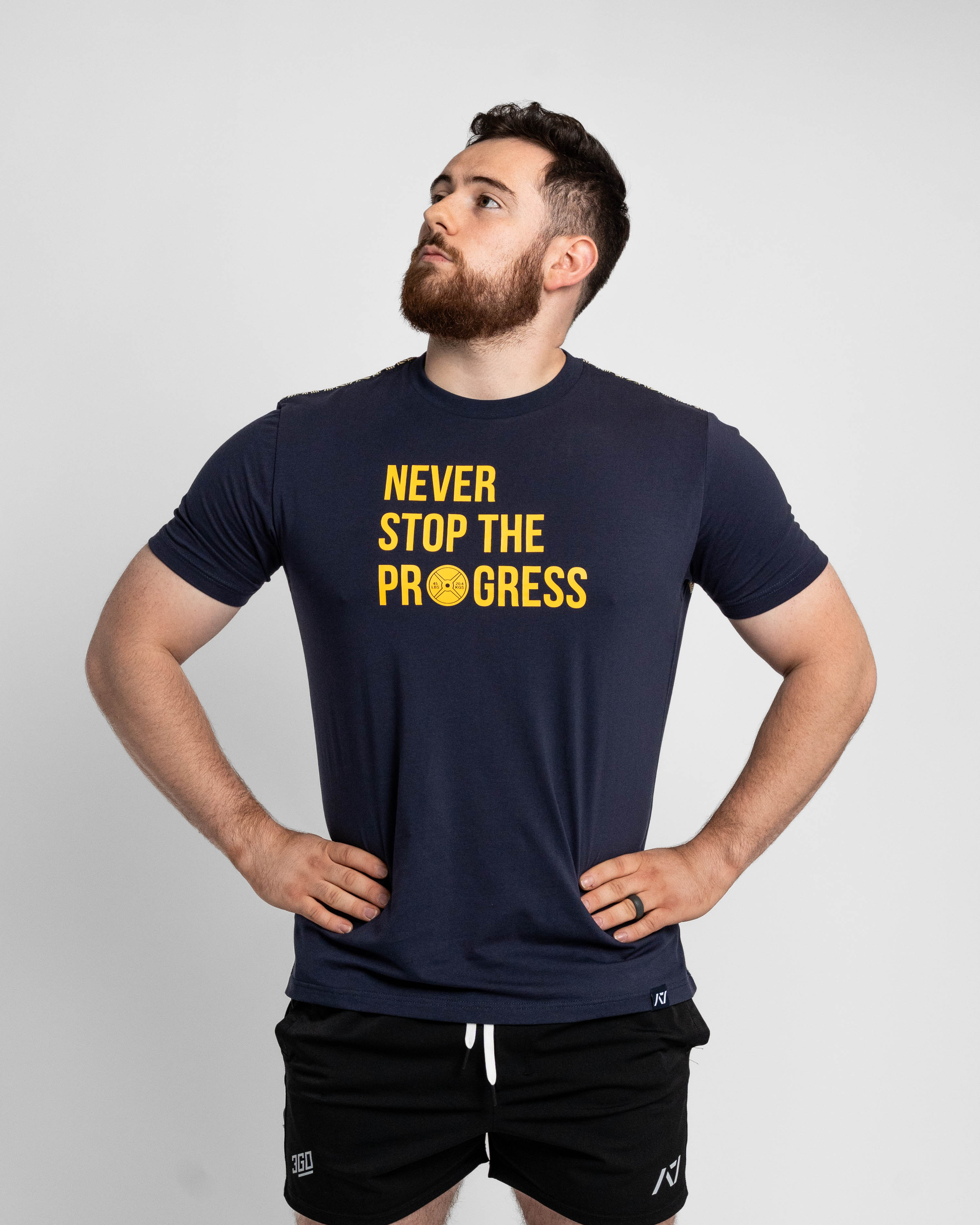 Man wearing a navy t-shirt with 'Never Stop The Progress' text on a light gray background