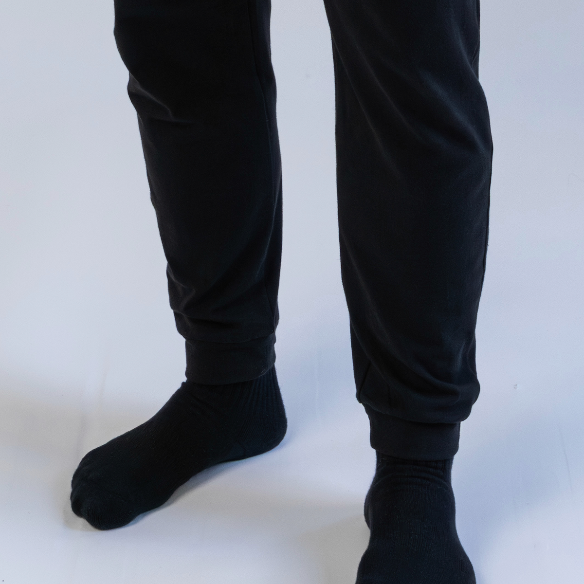 Person wearing black pants and socks on a white background