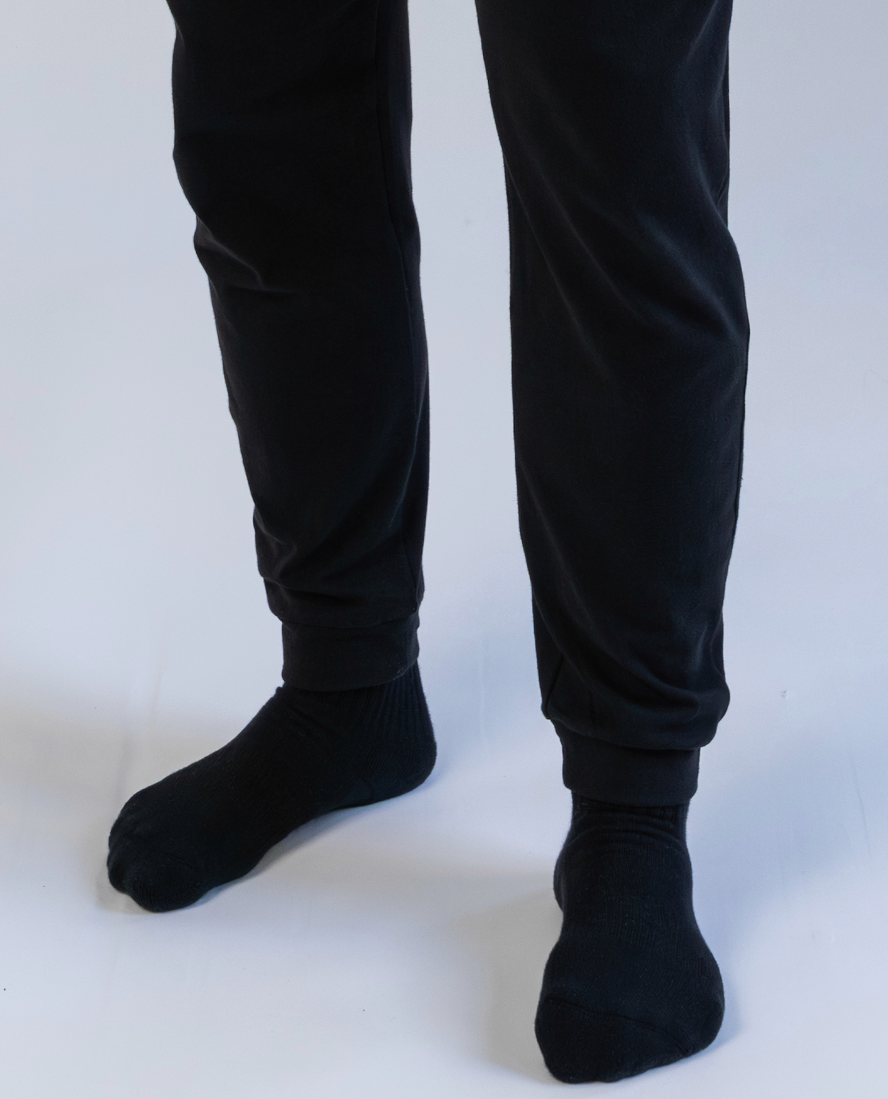 Person wearing black pants and socks on a white background