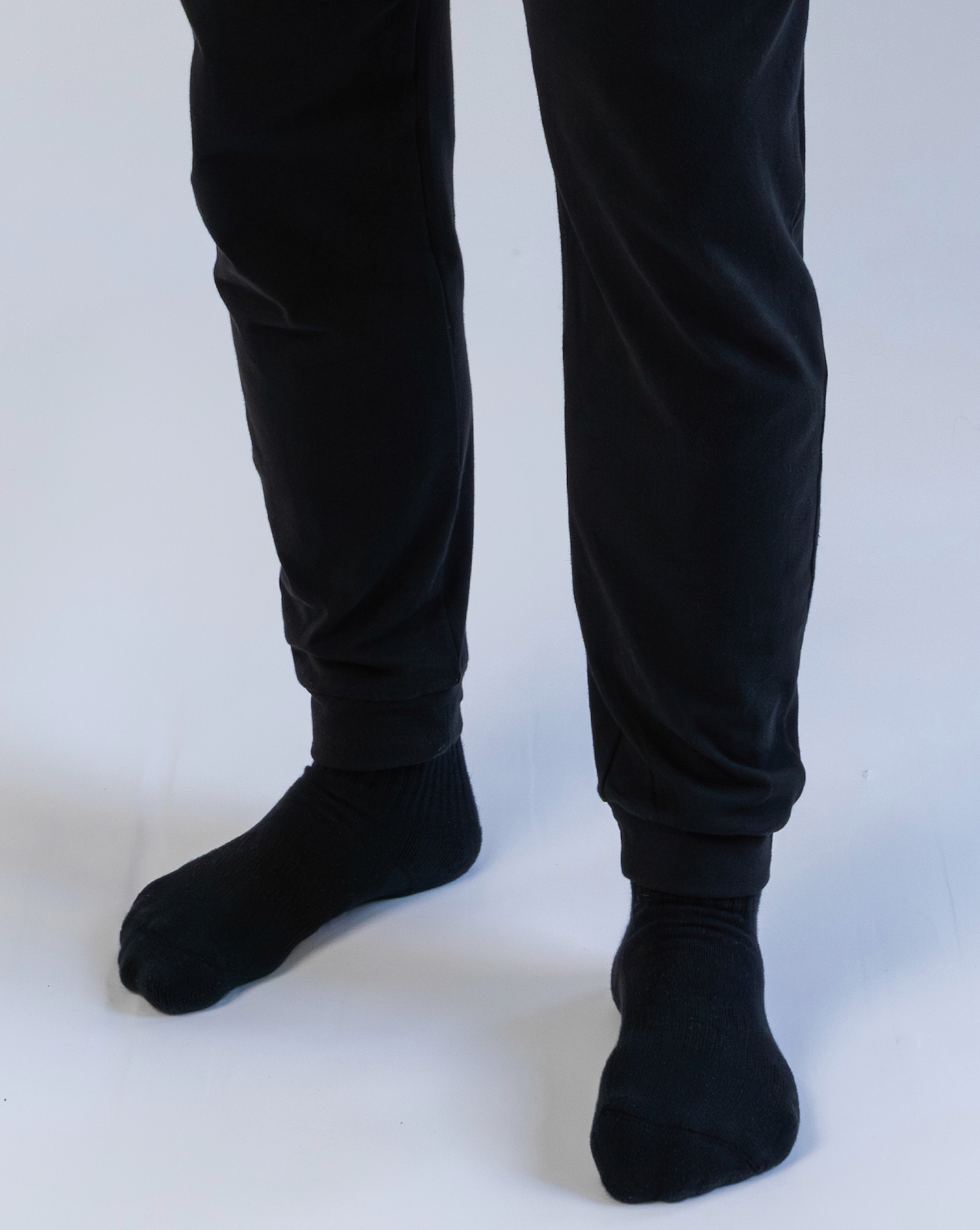 Person wearing black pants and socks on a white background