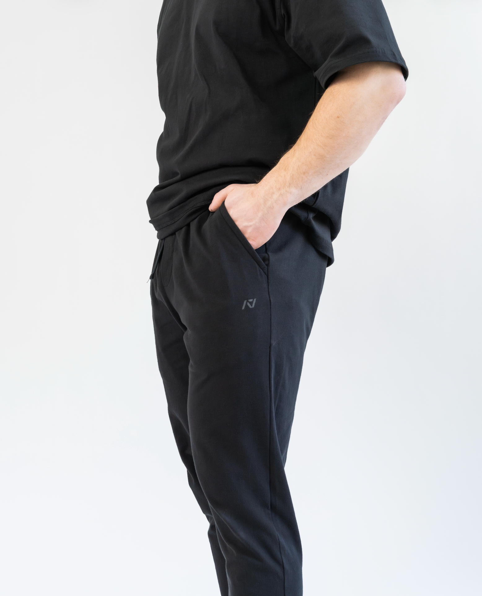 Person wearing black athletic pants and shirt on a white background