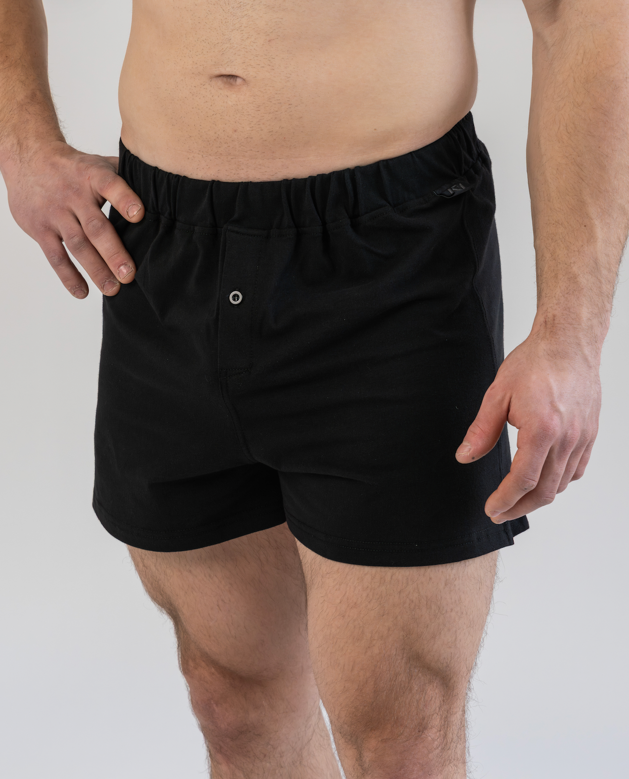 Person wearing black boxer shorts on a plain background