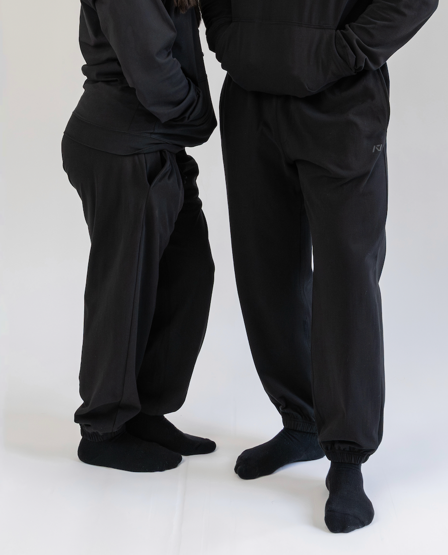 Two people wearing black pants and socks on a white background