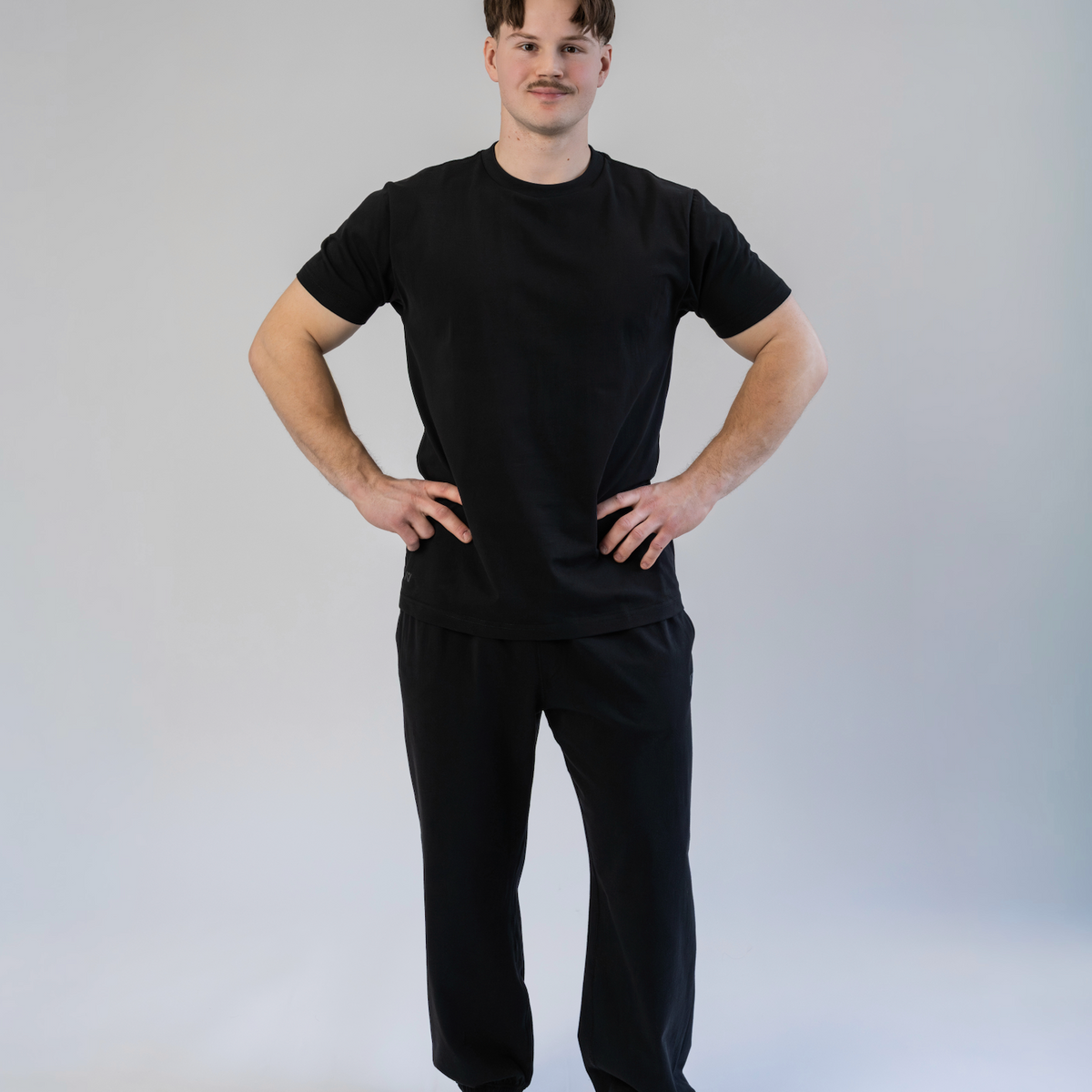 Person wearing a black t-shirt and black pants on a white background