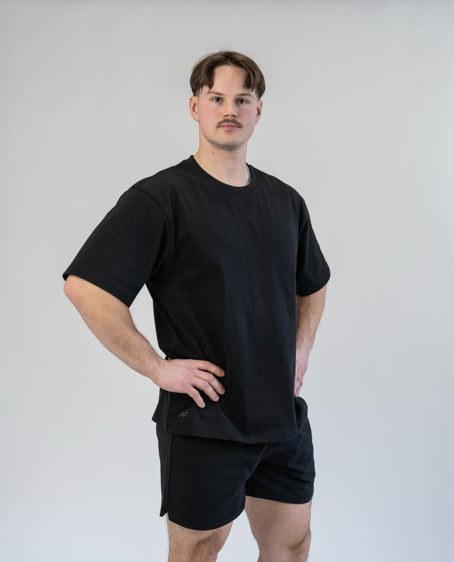 Man wearing a black t-shirt and shorts against a plain background