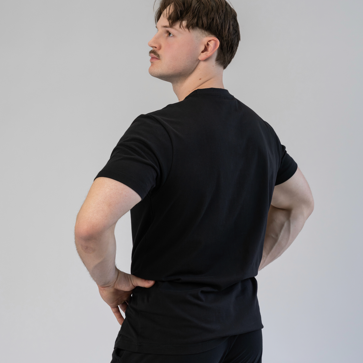 Person wearing a black t-shirt and pants against a plain background