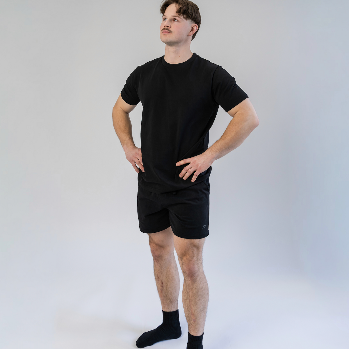 Person wearing a black t-shirt and shorts set on a white background