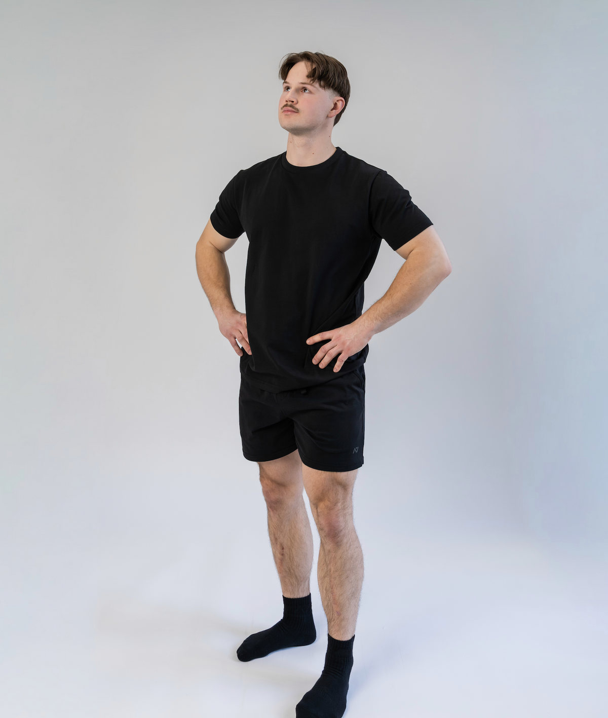 Person wearing a black t-shirt and shorts set on a white background