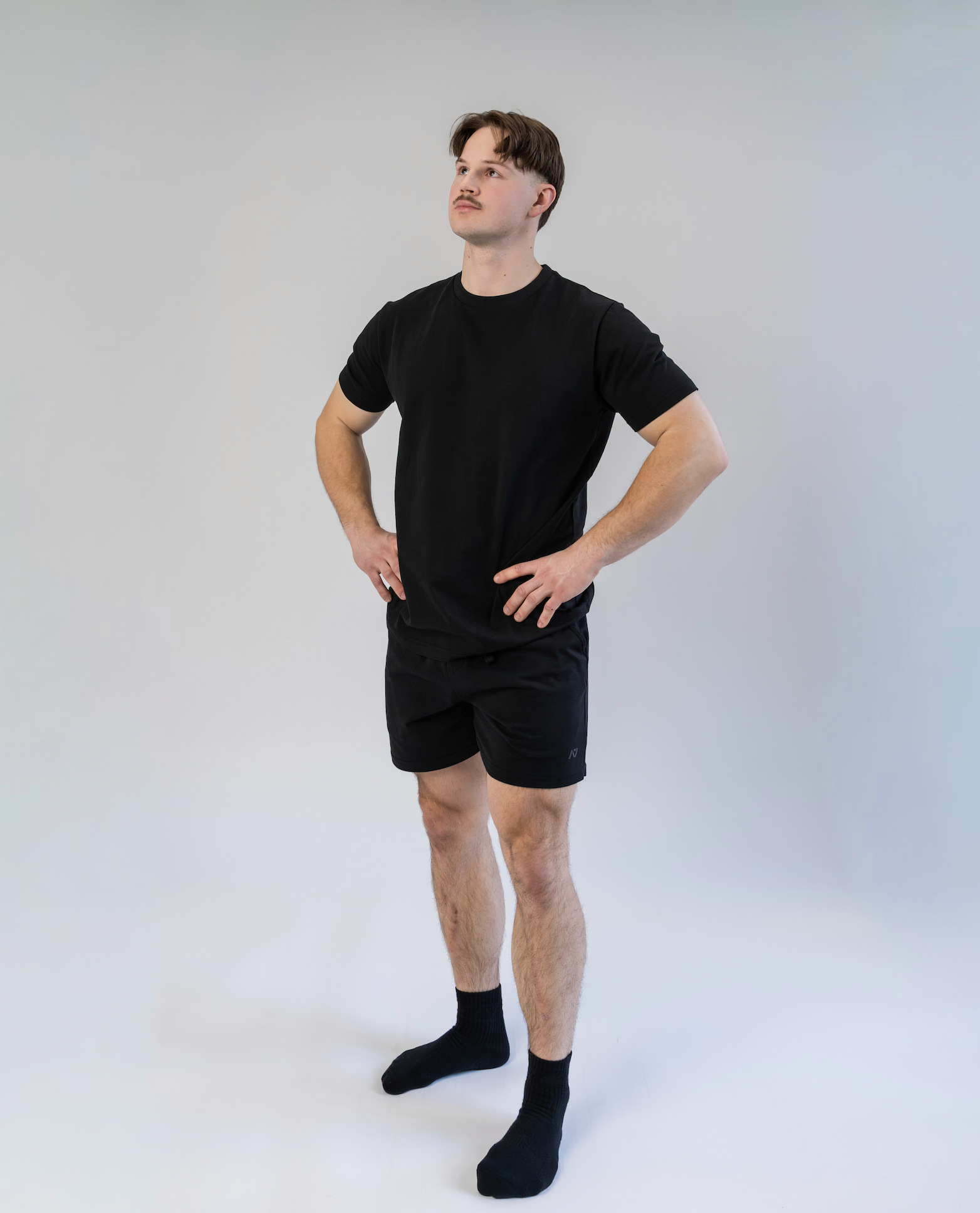Person wearing a black t-shirt and shorts set on a white background