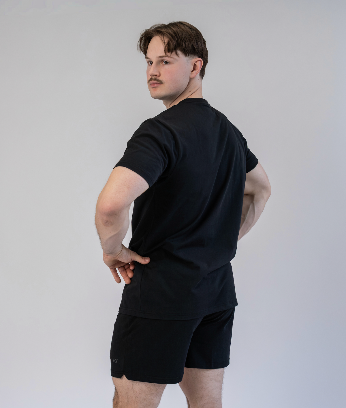 Man wearing a black t-shirt and shorts against a plain background
