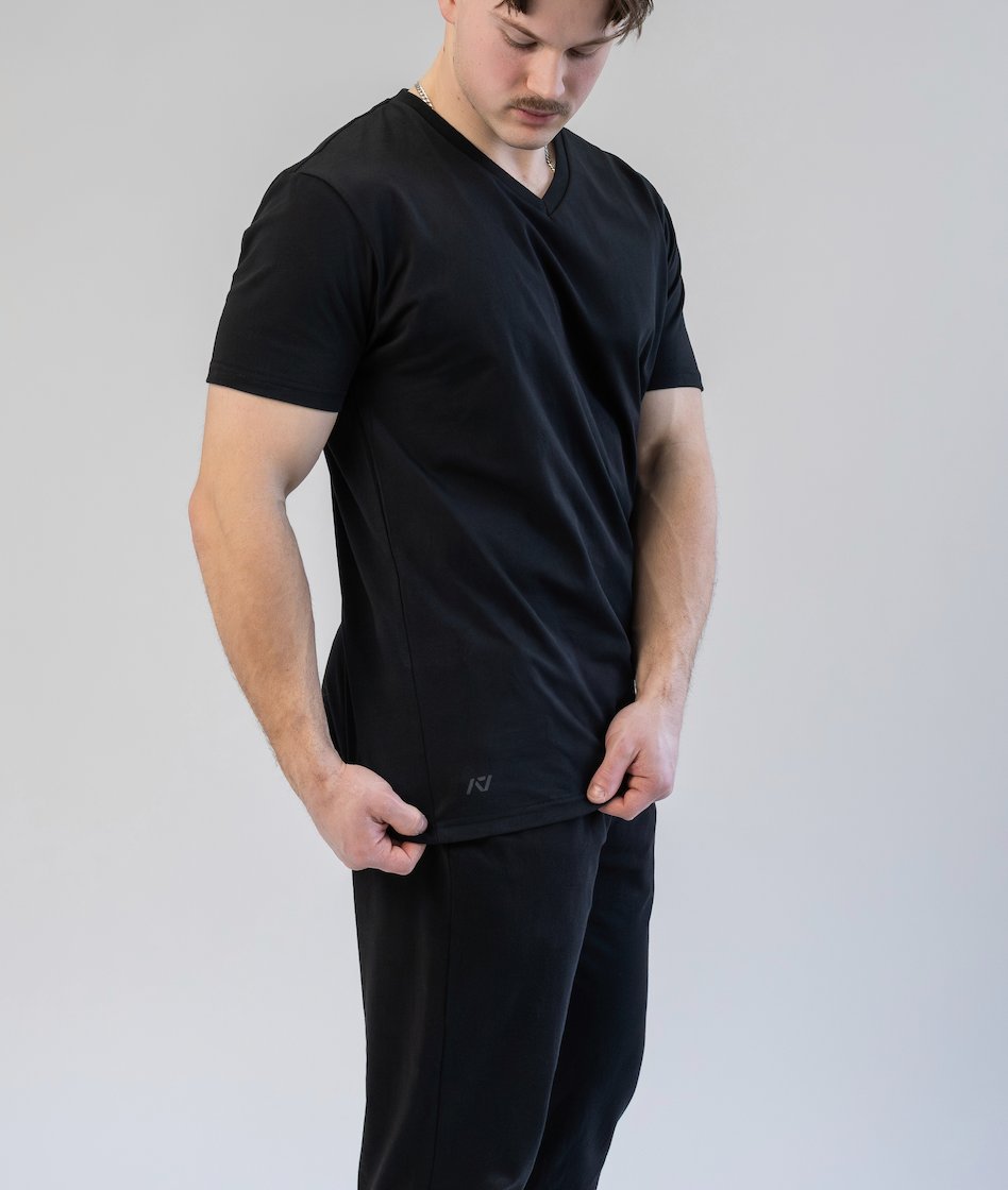 Man wearing a black t-shirt and pants on a plain background