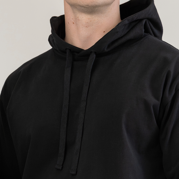 Person wearing a black hoodie against a plain background