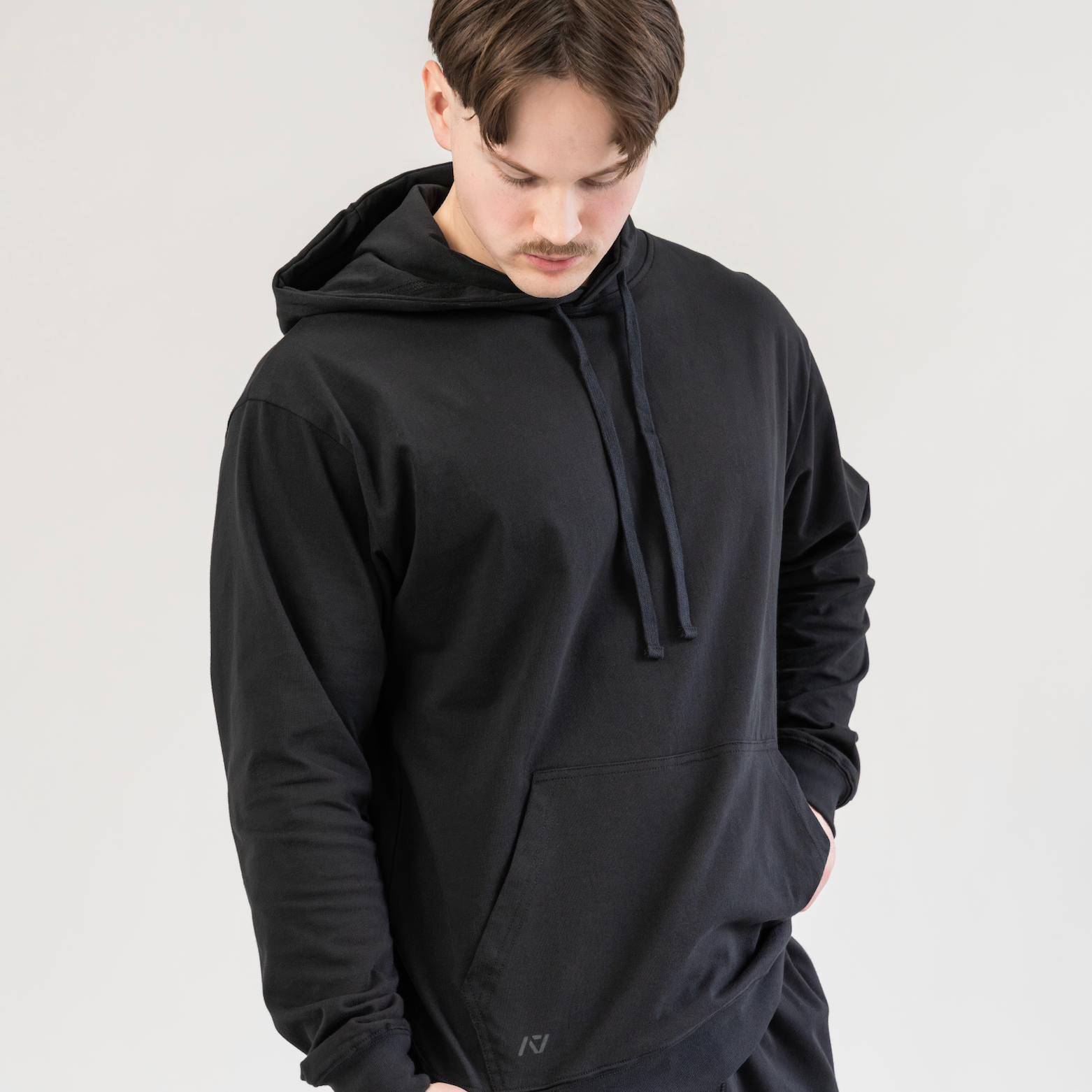 Man wearing a black hoodie and pants against a plain background