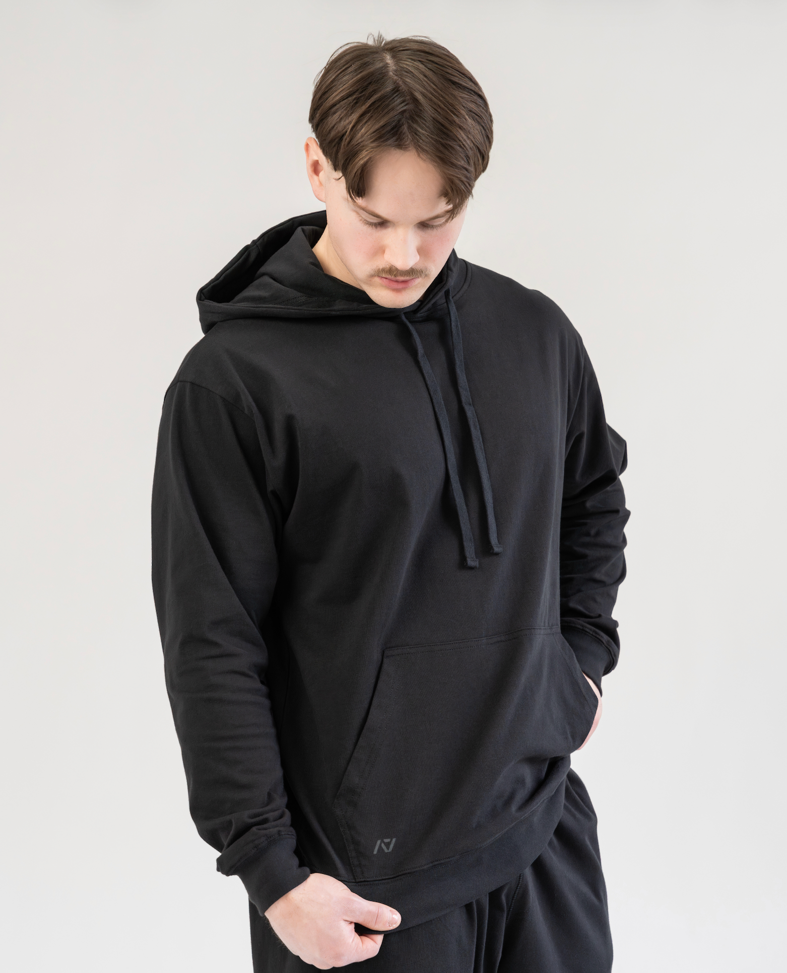 Man wearing a black hoodie and pants against a plain background